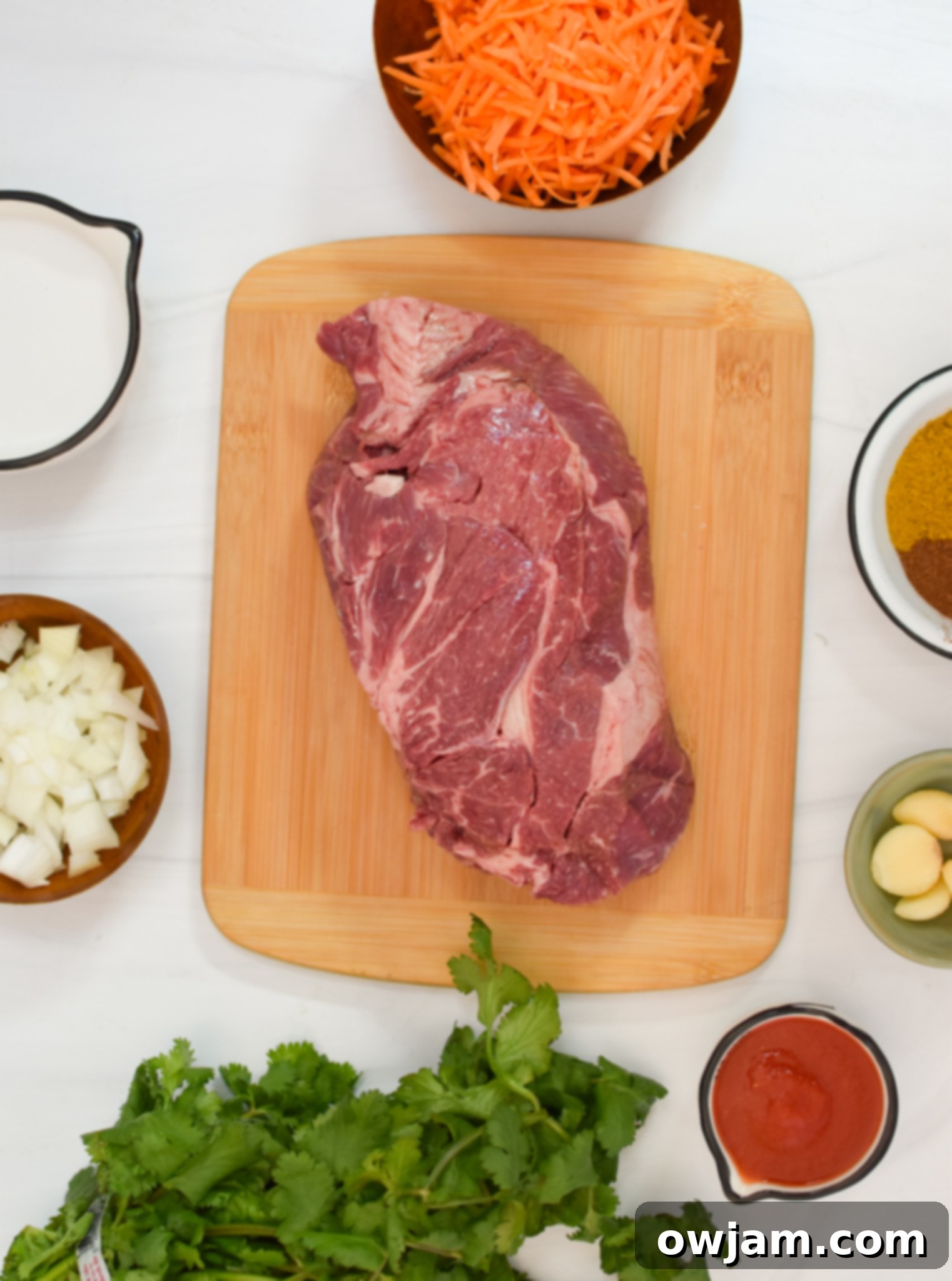 Selection of fresh ingredients for Slow Cooker Beef Curry, including beef, carrots, ginger, garlic, and Indian spices.
