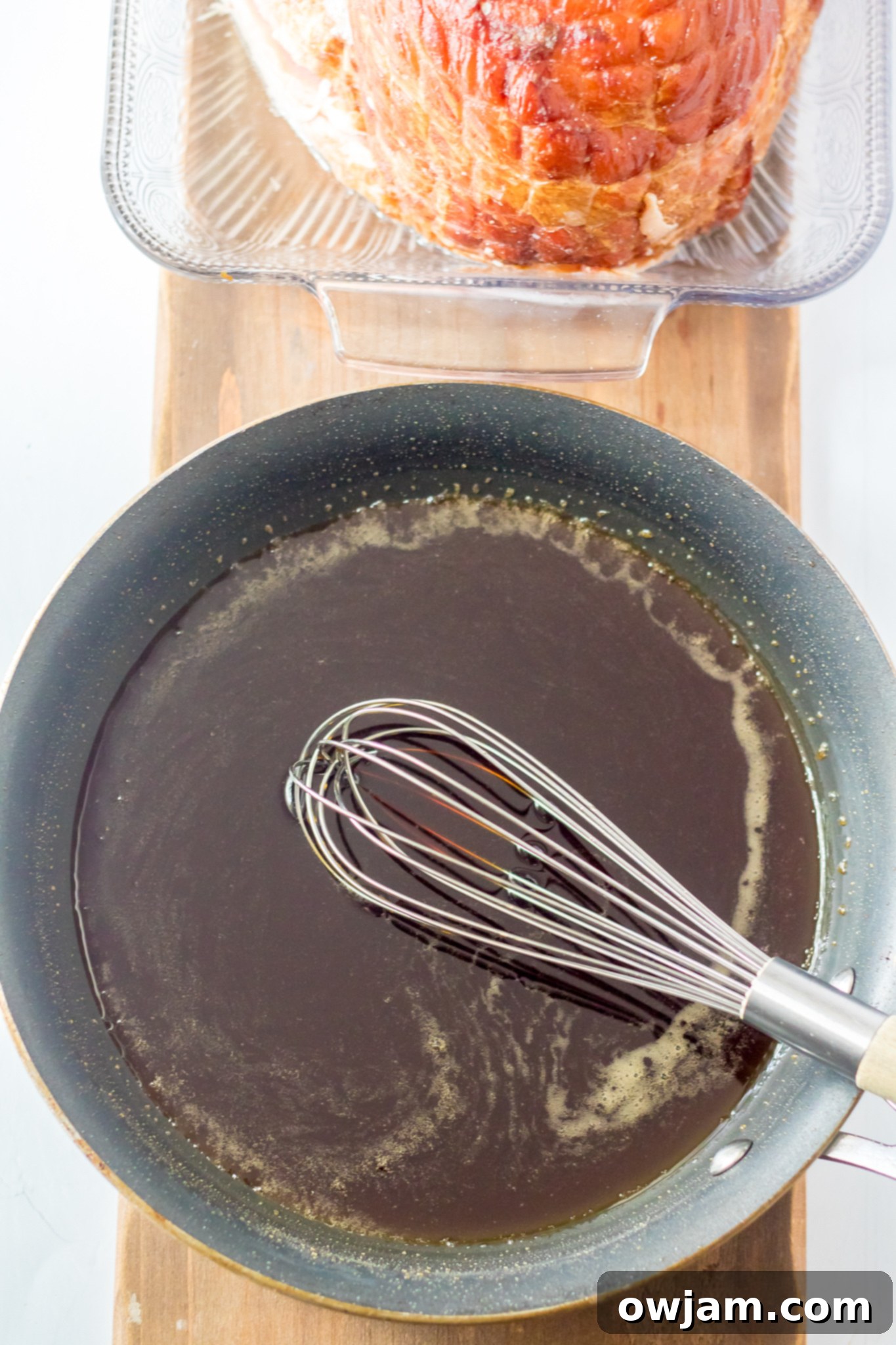 Close-up of the reduced apple cider glaze in a saucepan, showing its thick, syrupy consistency.