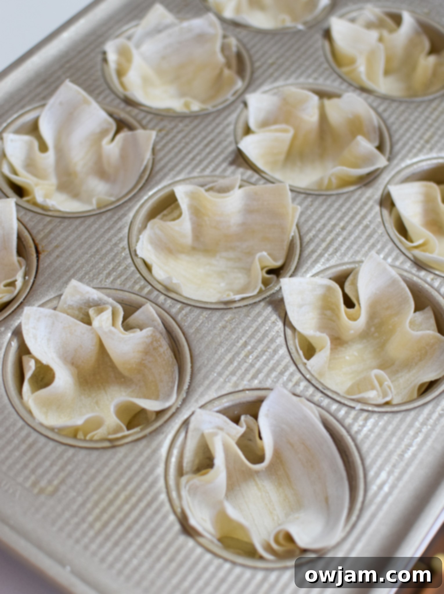 Crispy Mediterranean Feta Parcels 6 Mediterranean Quiche Wontons being assembled in a muffin tin.