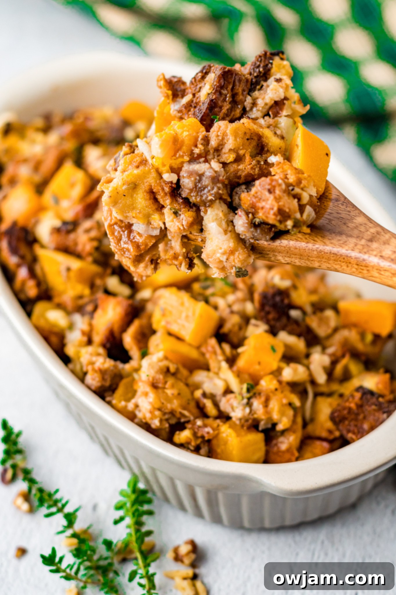 Autumn Butternut Dressing 11 A delicious serving of Butternut Squash Stuffing in a white casserole dish with a serving fork, ready to be enjoyed.