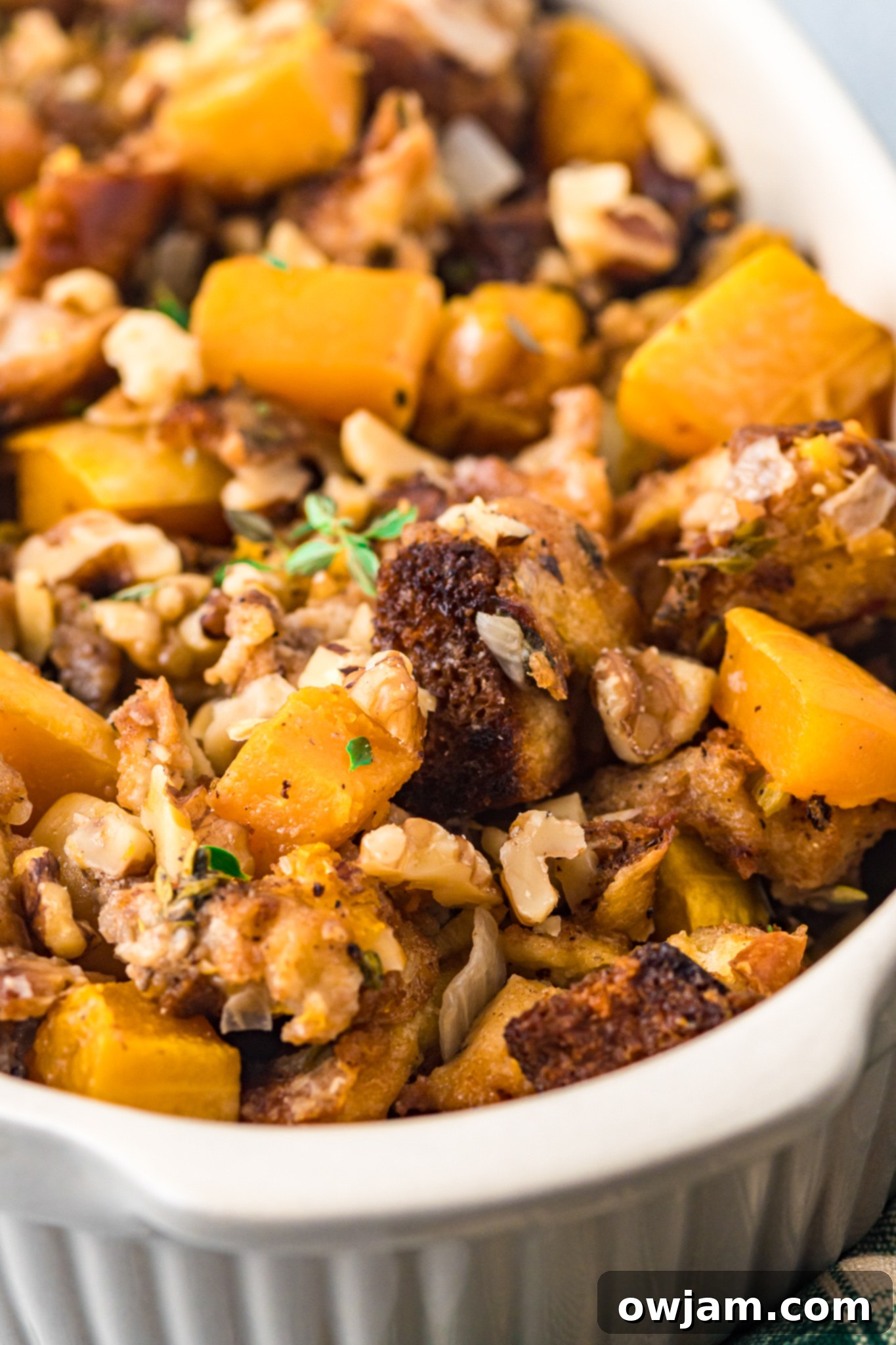 Autumn Butternut Dressing 4 Butternut Squash Stuffing garnished with vibrant fresh thyme sprigs, showcasing its rich texture.