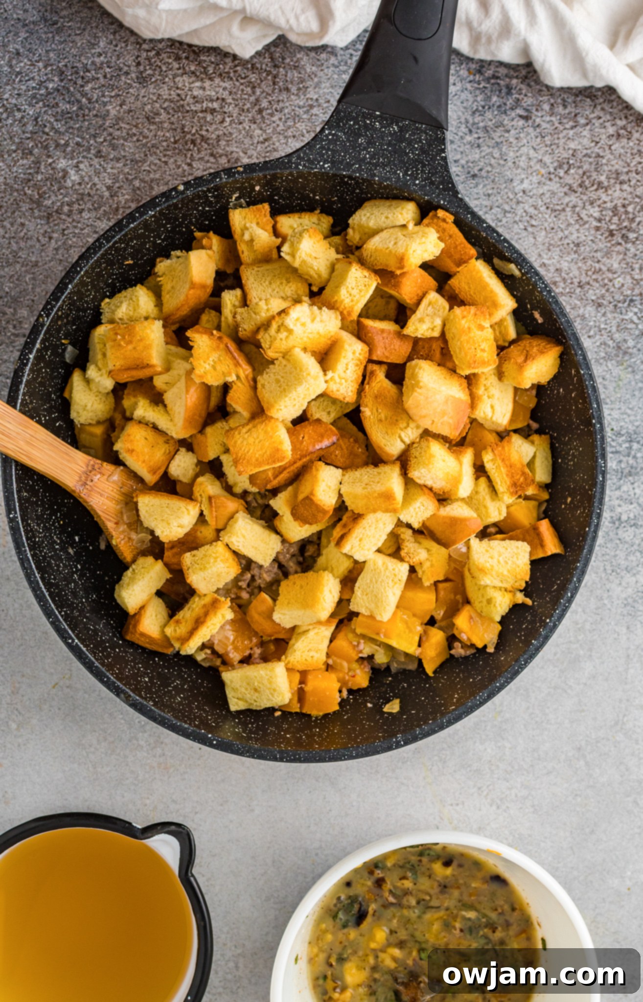 Autumn Butternut Dressing 9 Dried Italian bread cubes tossed with the butternut squash and sausage mixture in a large bowl, ready for broth.