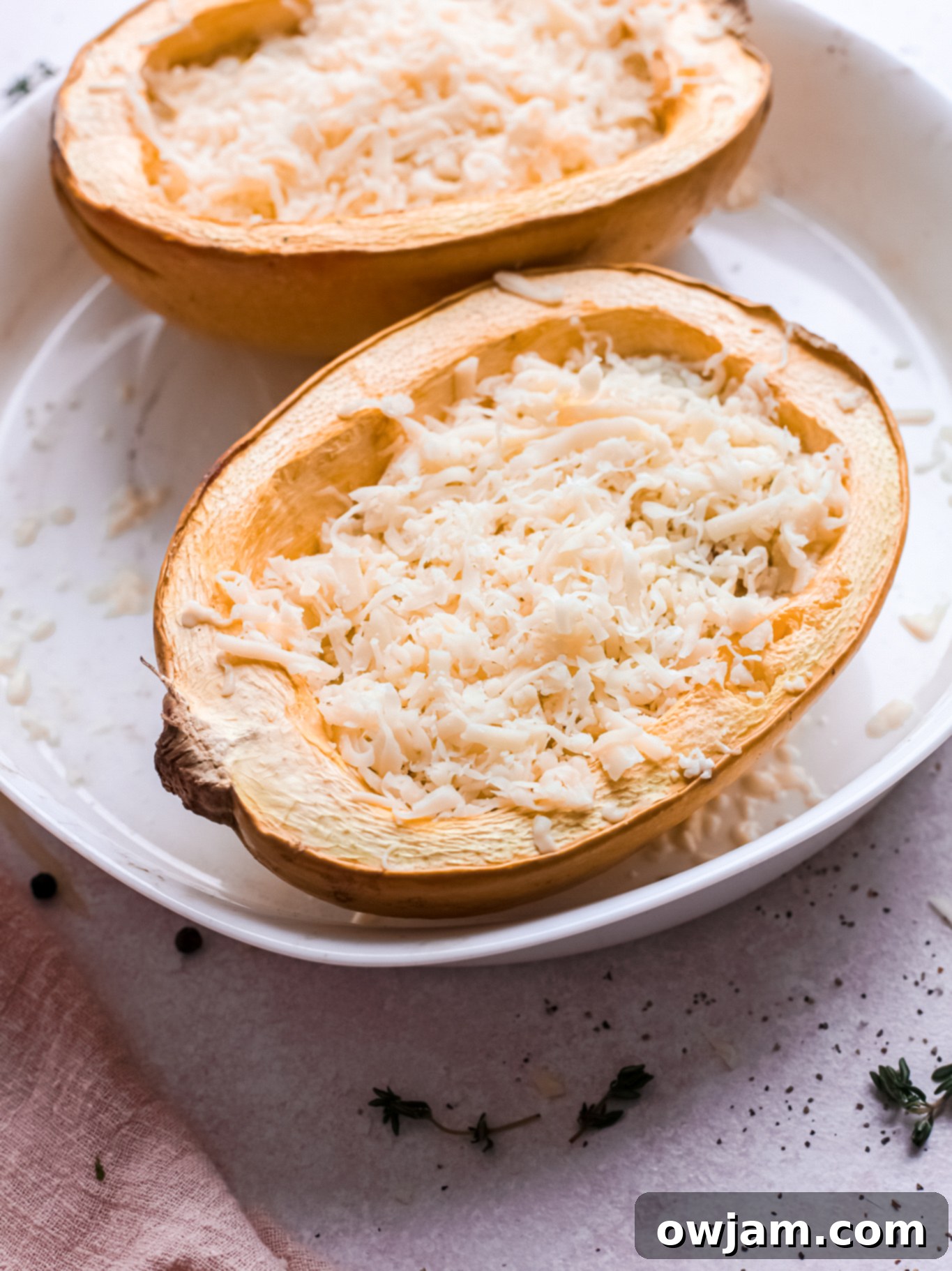 Baked spaghetti squash halves with cheese mixture on top, ready for final baking.