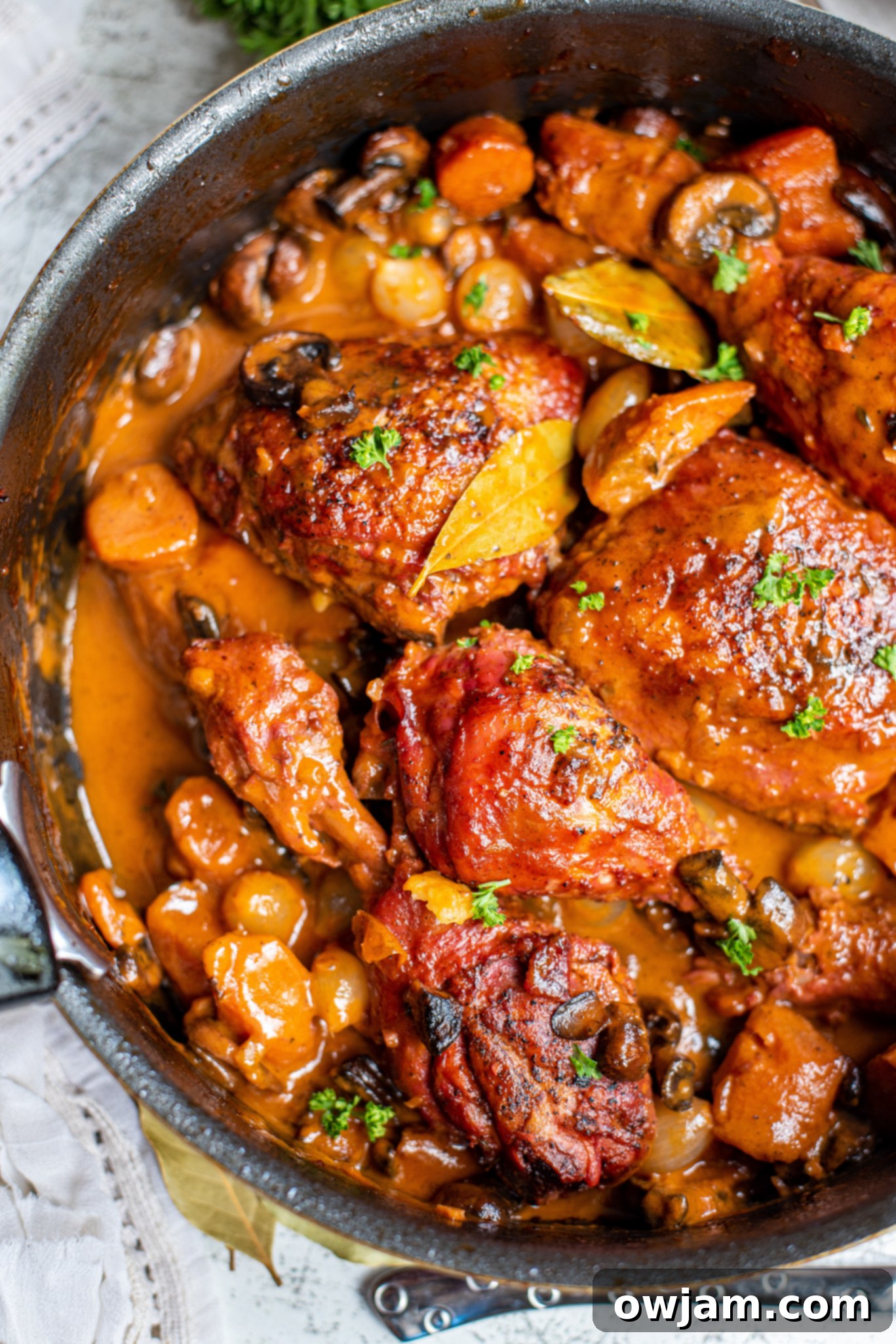 Finished Coq au Vin Recipe in a Dutch oven, garnished with fresh parsley.