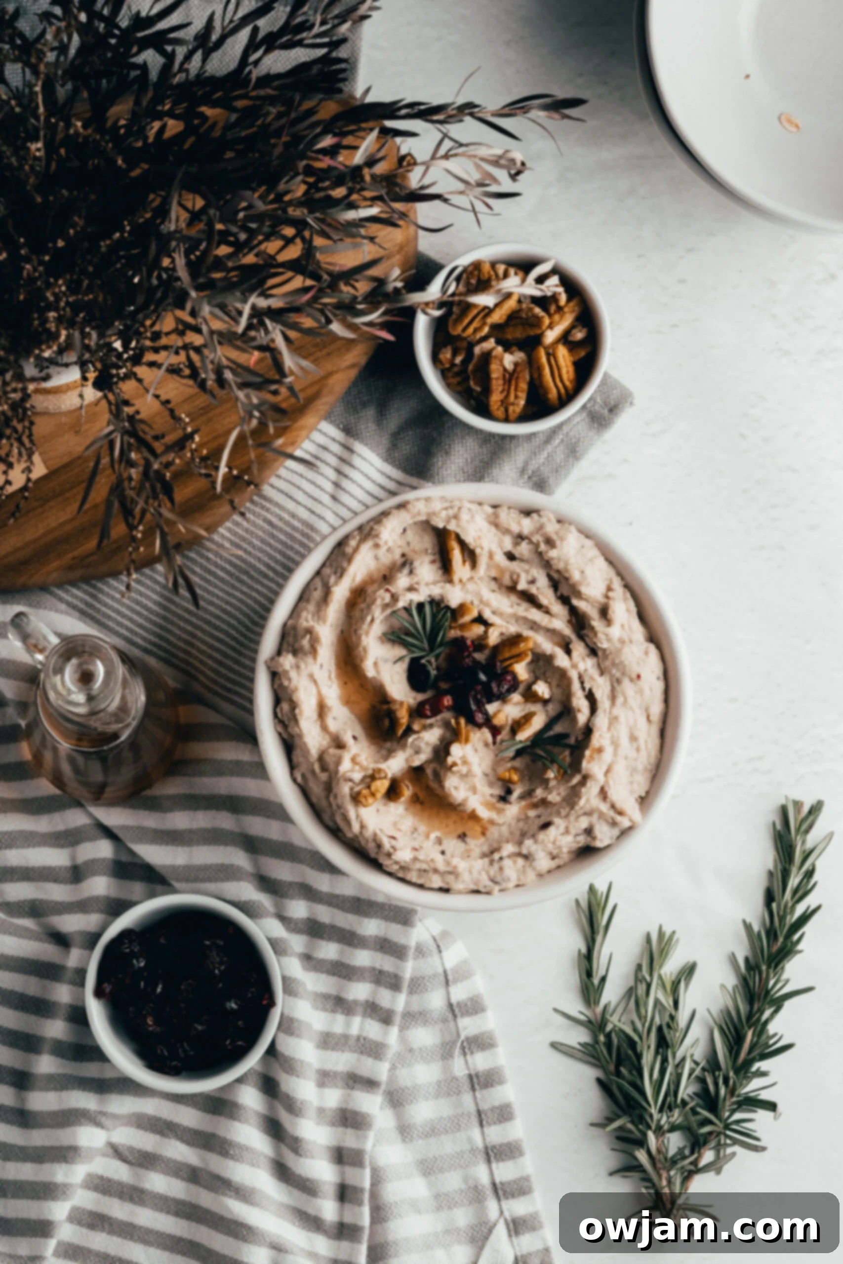 Festive Cranberry White Bean Hummus 6 Overhead view of a beautifully garnished White Bean Hummus with Cranberry, topped with pecans and rosemary.