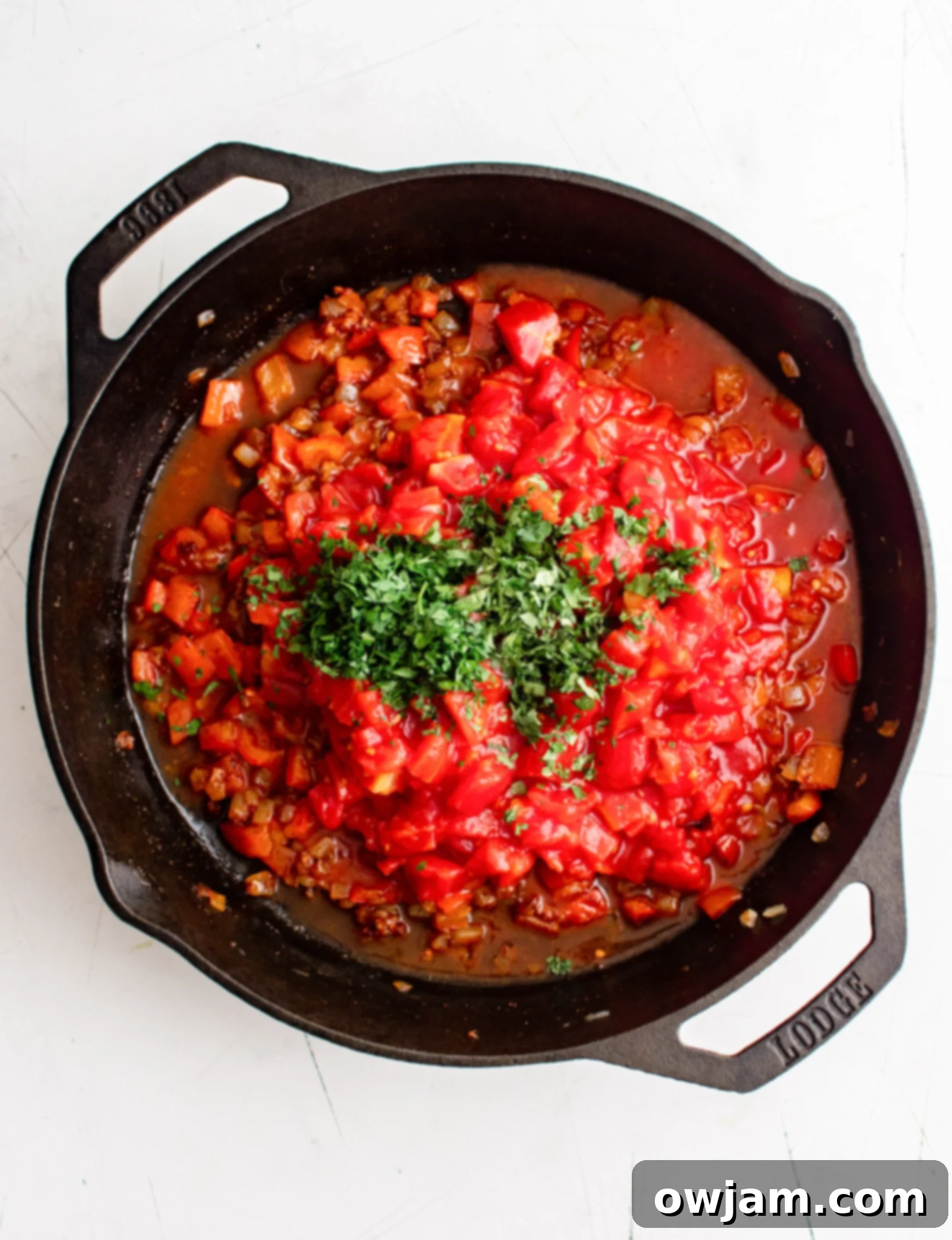 Effortless Shakshuka 8 Adding diced tomatoes and fresh herbs to the shakshuka sauce.