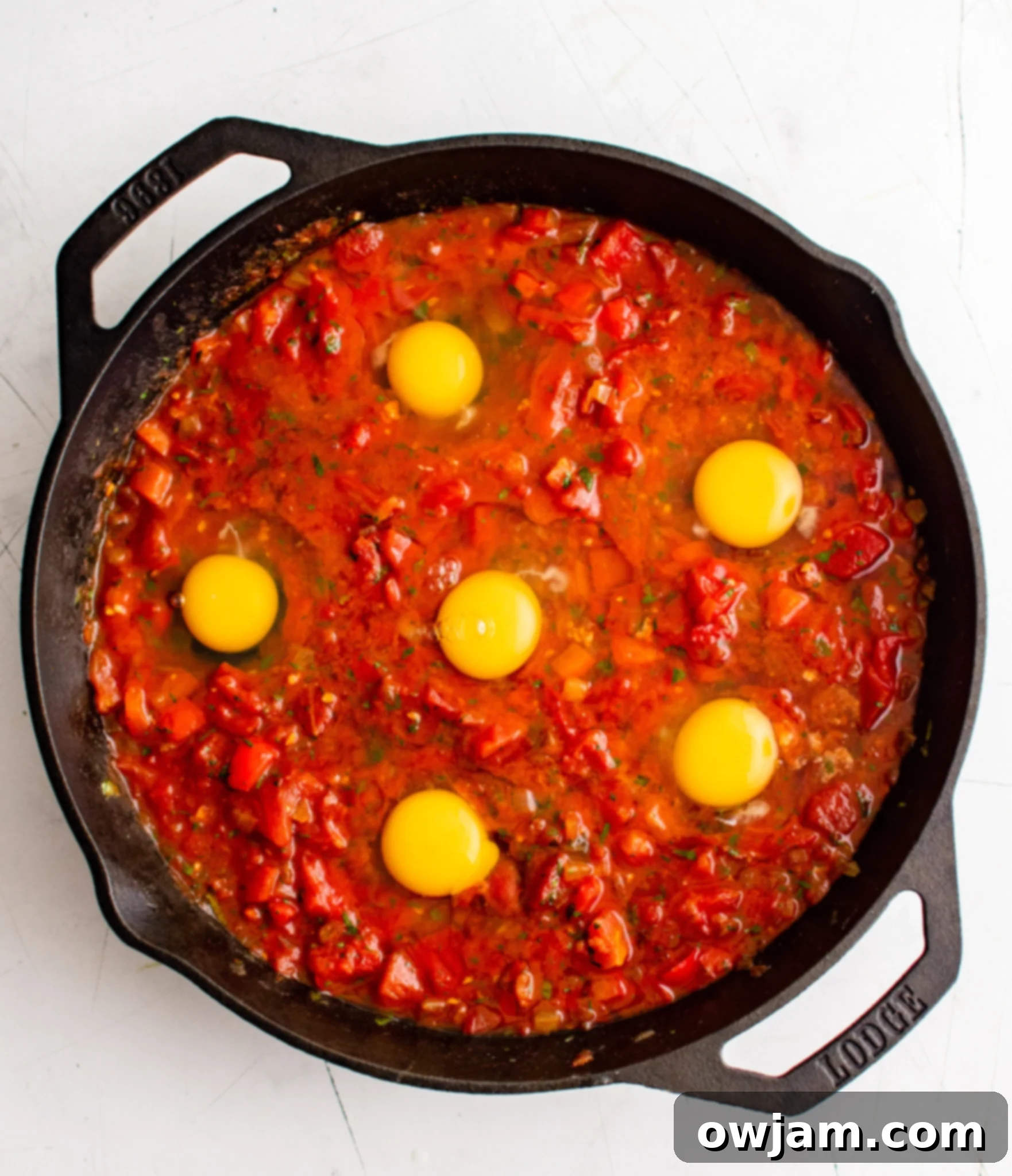 Effortless Shakshuka 9 Eggs cracked into the simmering shakshuka sauce.