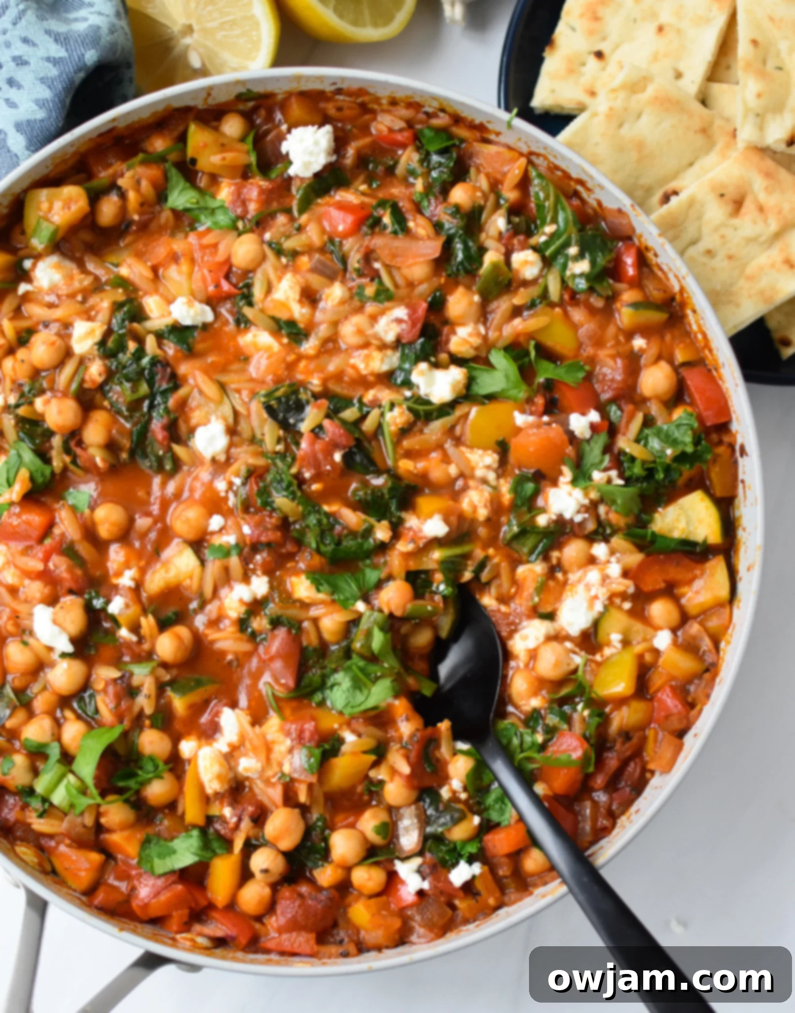 Mediterranean Orzo Pasta Recipe in a pan, garnished with fresh herbs and feta.