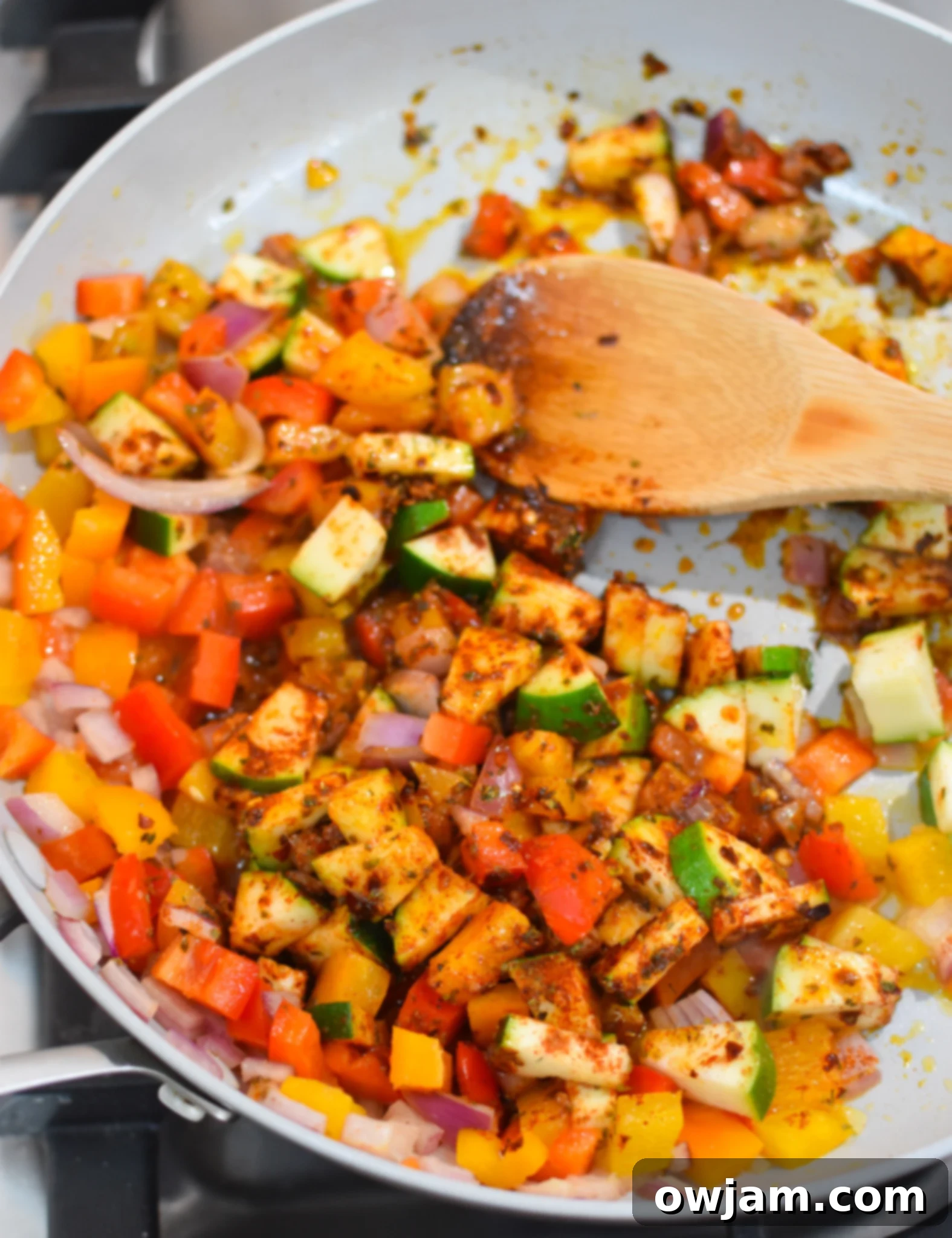 Sautéed vegetables and spices in a skillet for Mediterranean Orzo Pasta.