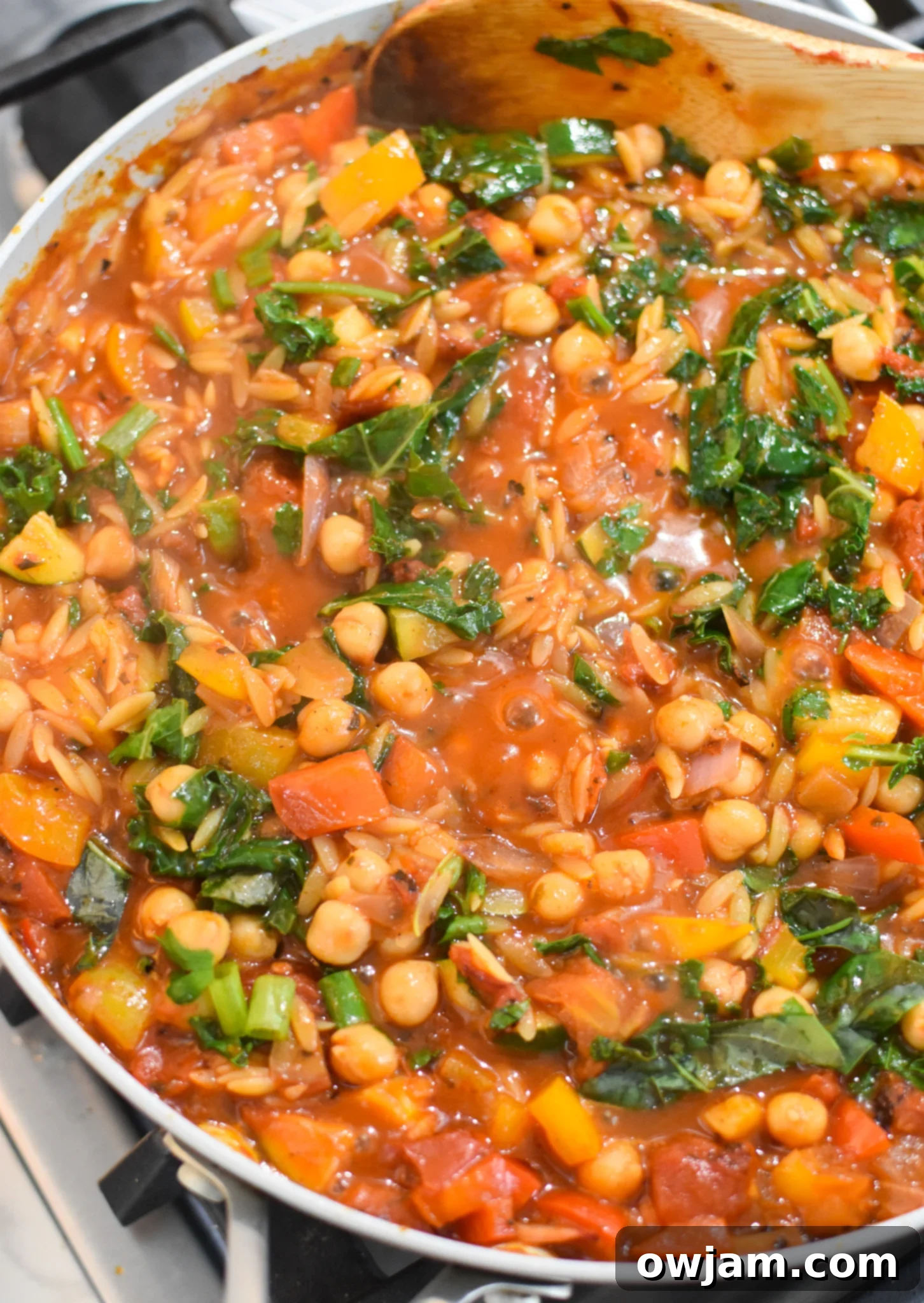 Mediterranean Orzo Pasta with vegetables and chickpeas simmering in a pan.