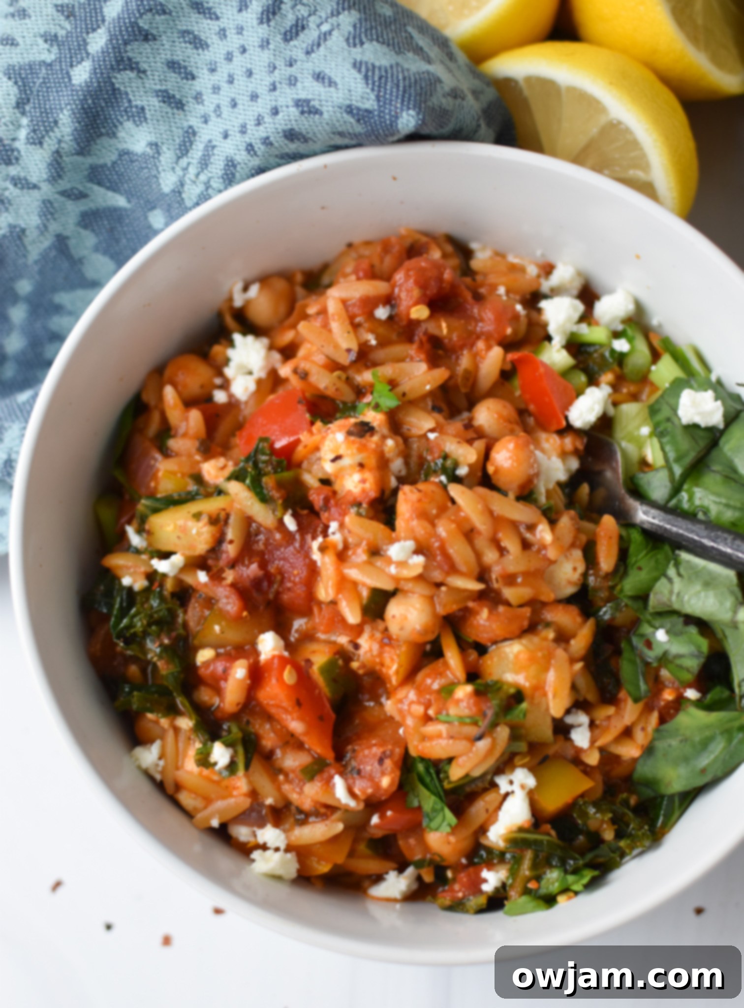 A close-up of Mediterranean Orzo Pasta in a bowl with a serving spoon.