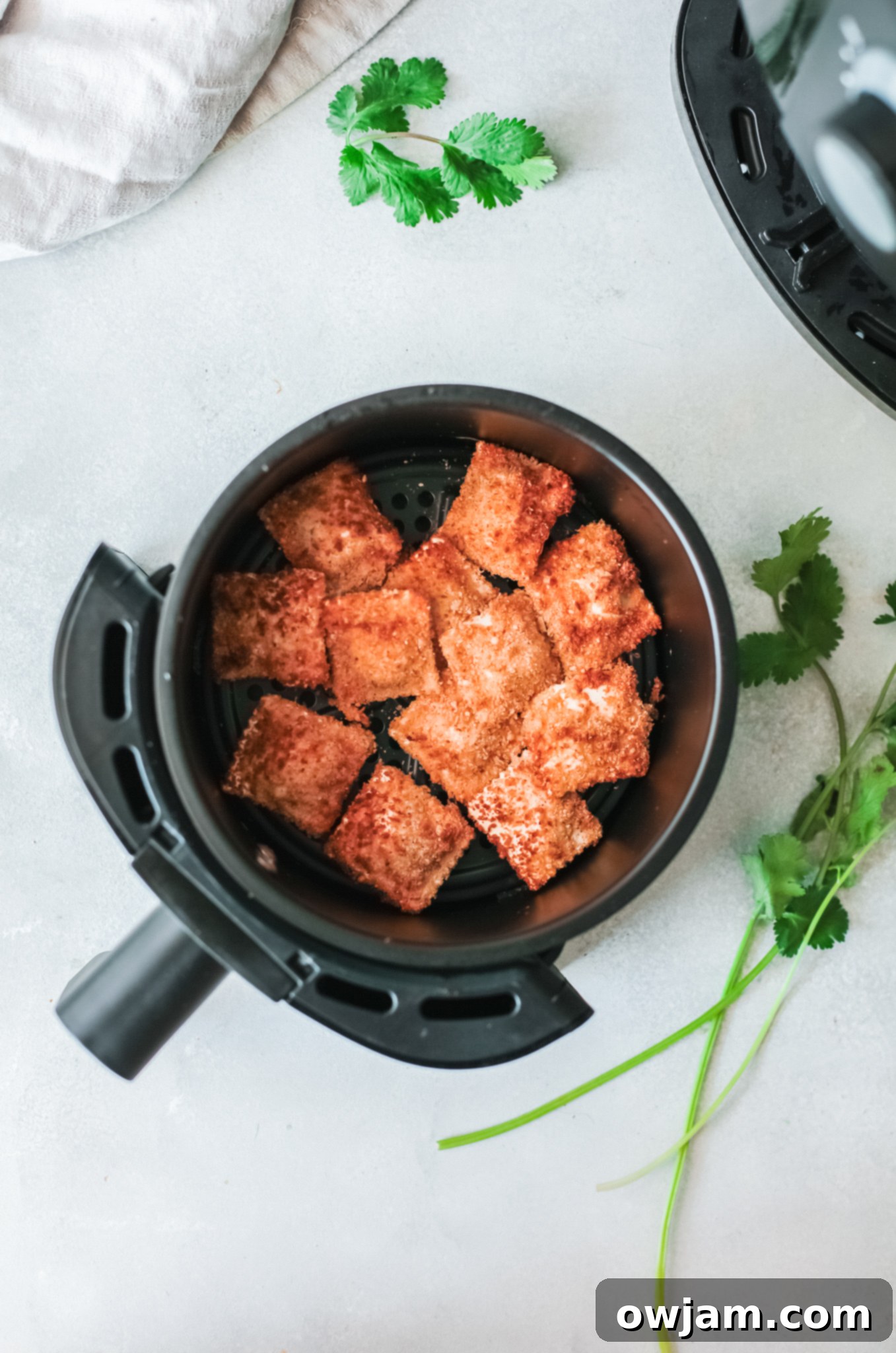 Air Fried Ravioli cooking in an air fryer basket, becoming golden brown.