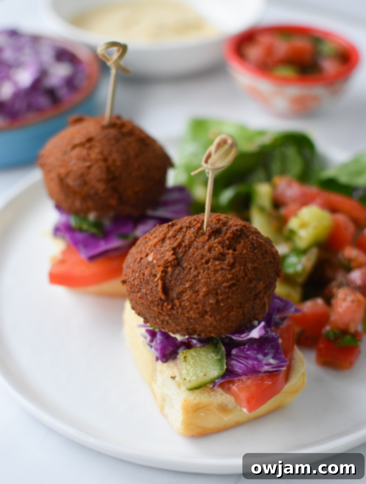Falafel Sliders with Tangy Tahini Slaw 4 Falafel Sliders with Tahini Slaw on a white plate. A close-up shot of a single, perfectly crafted falafel slider on a minimalist white plate, highlighting its vibrant layers.