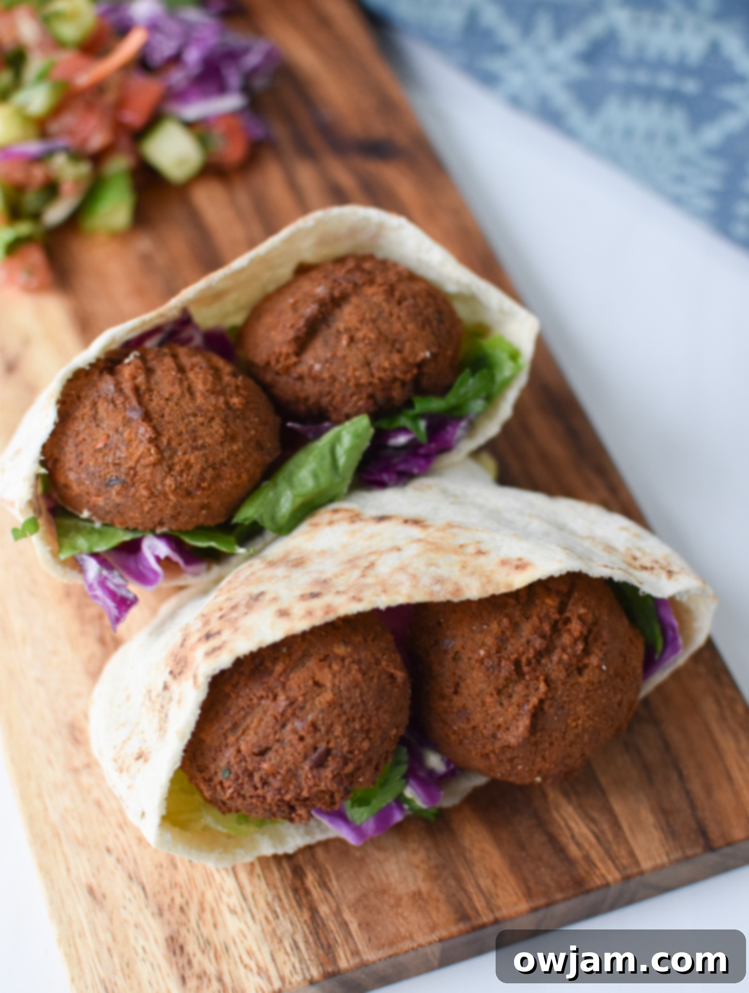 Falafel Sliders with Tangy Tahini Slaw 5 Falafel Sliders with Tahini Slaw on a cutting board. A platter of falafel sliders is arranged on a cutting board, garnished with fresh herbs, inviting a taste.