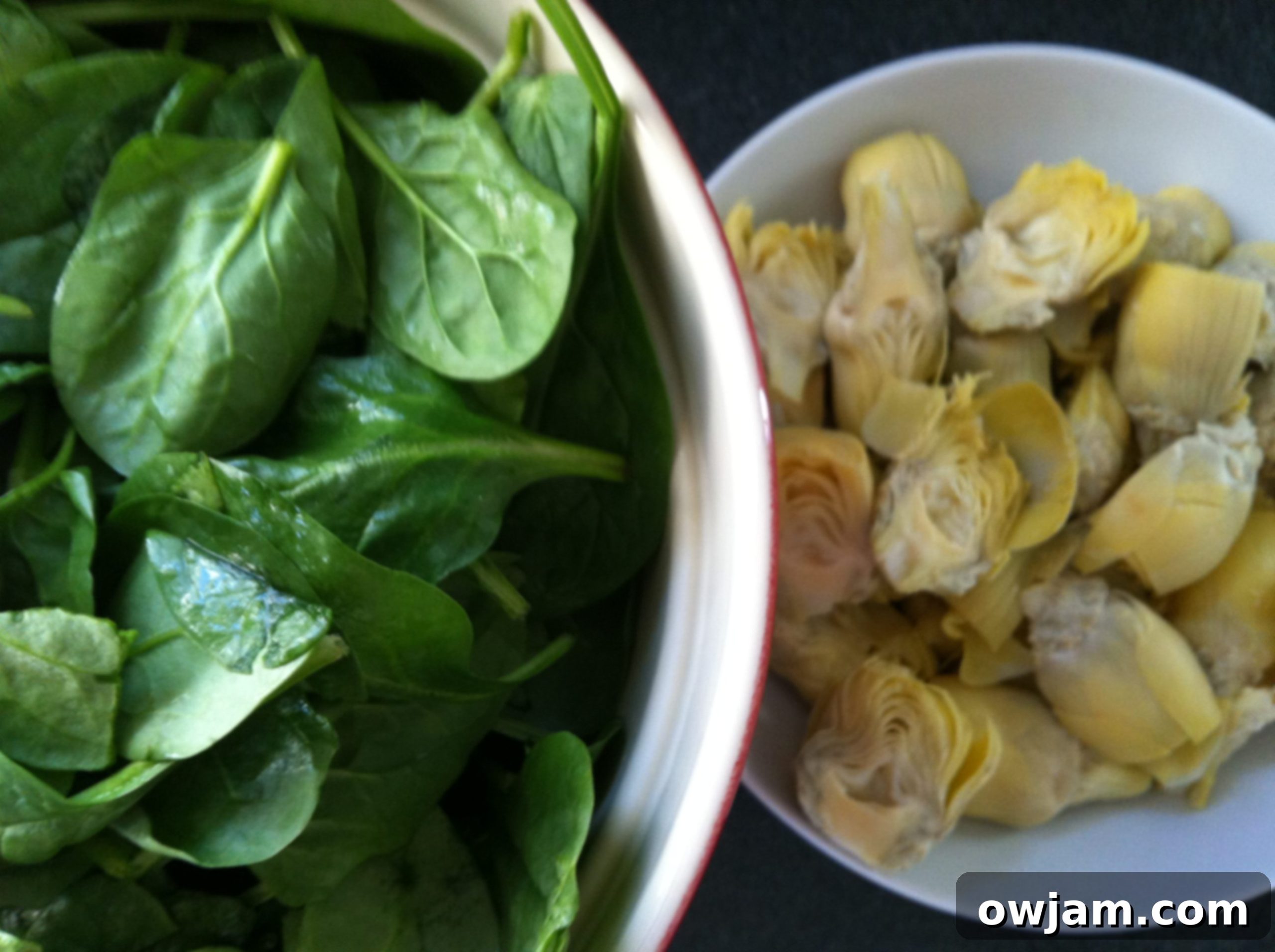 Close-up of creamy spinach artichoke pasta in a bowl, showing the texture