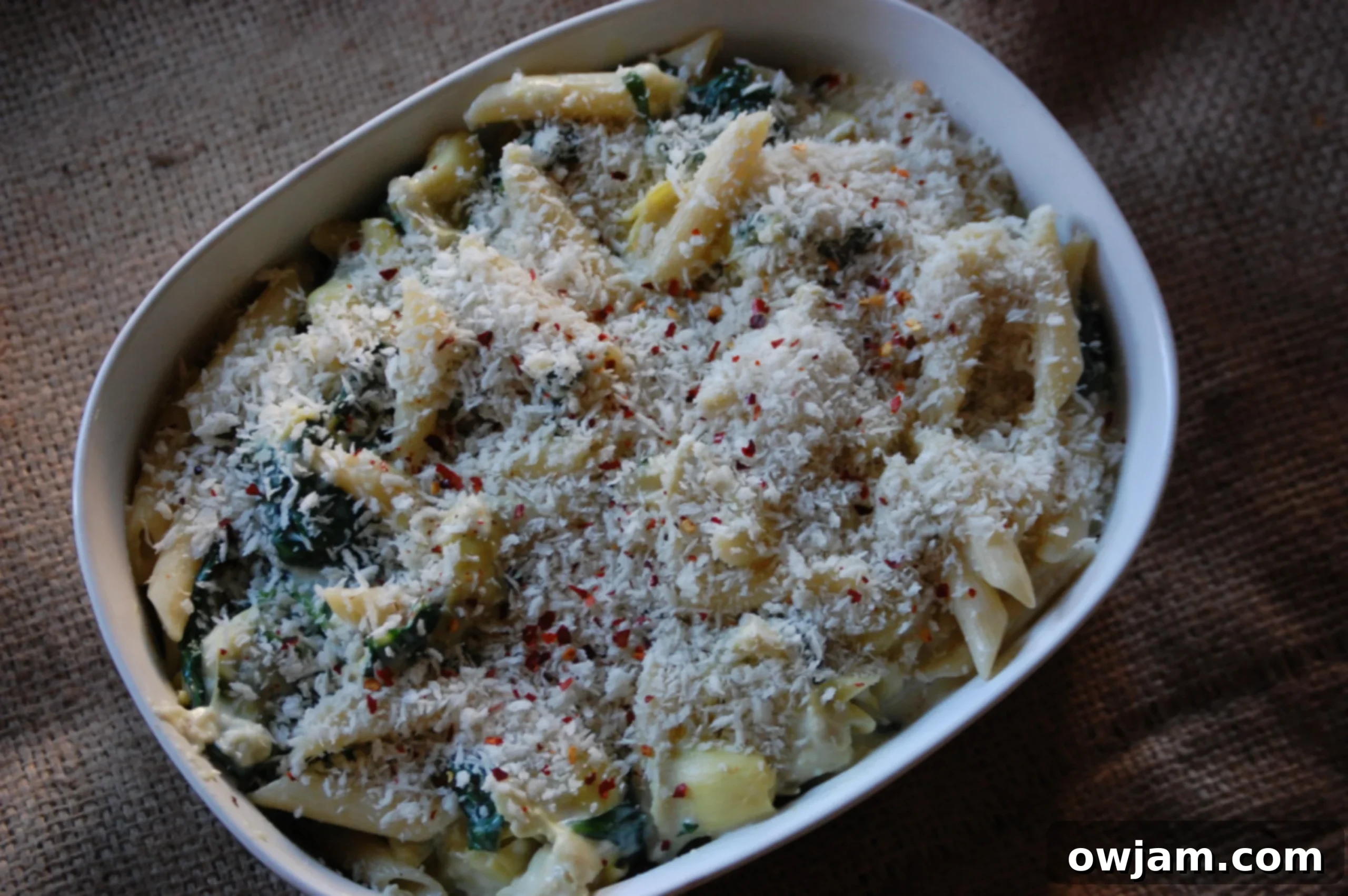 Plated Spinach Artichoke Pasta, garnished with fresh herbs and panko