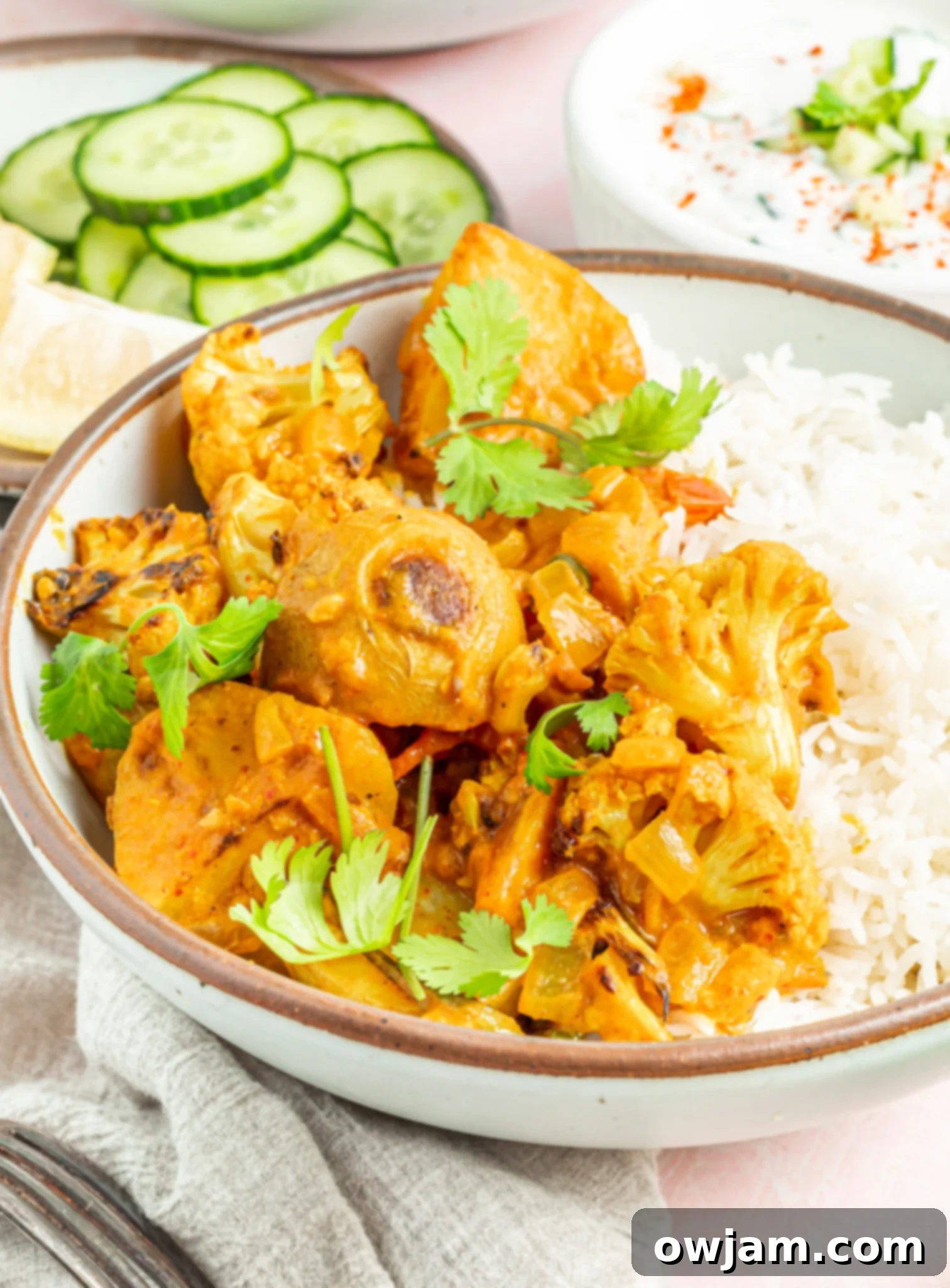 Golden Cauliflower Curry 4 Finished Creamy Cauliflower Curry with roasted potatoes, garnished generously with fresh cilantro in a white serving bowl.