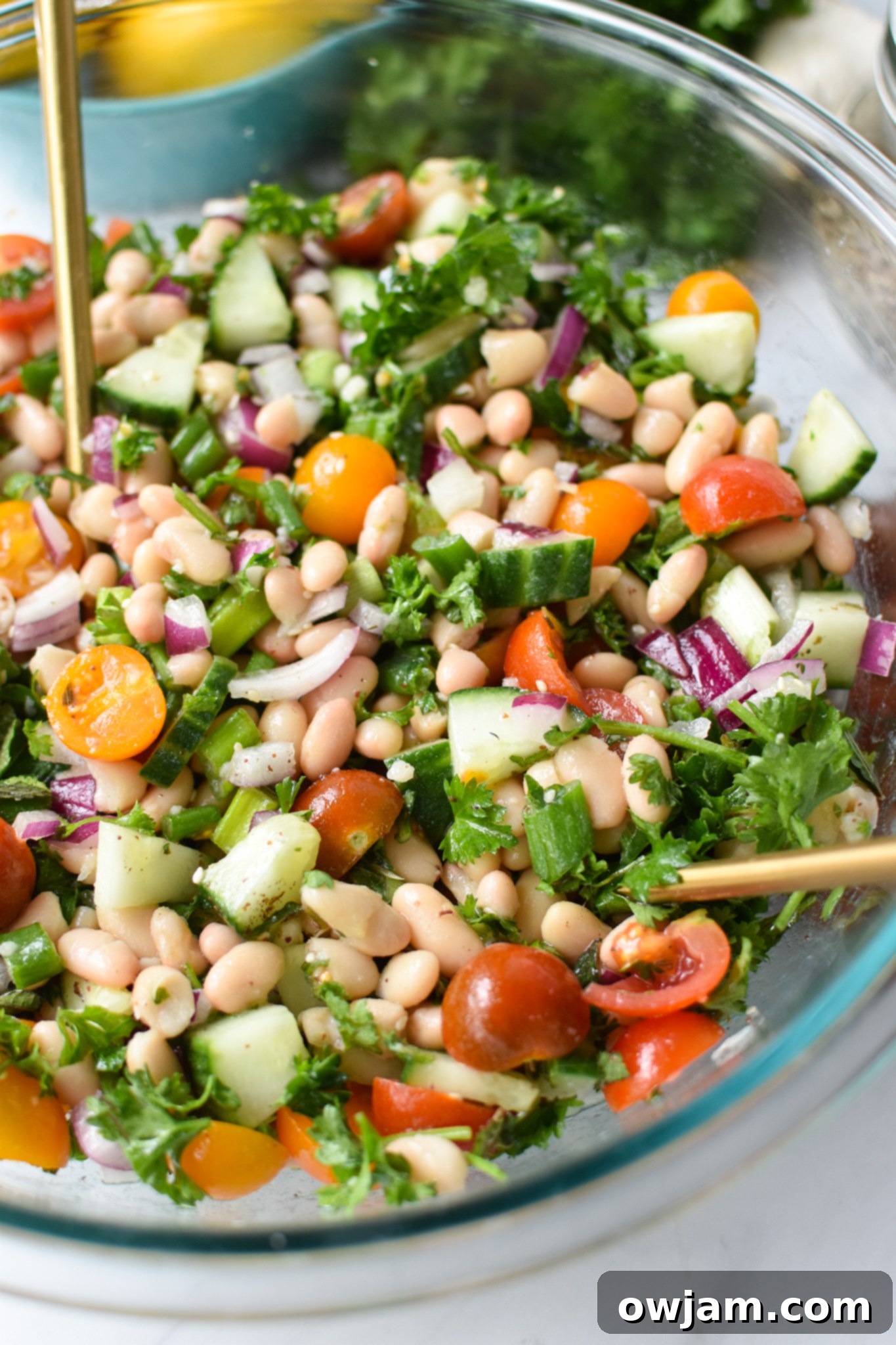 Sun Drenched White Bean Medley 2 Mediterranean White Bean Salad with gold spoons, highlighting fresh ingredients.
