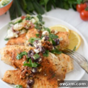 Greek Baked Tilapia with a fork on a white plate.