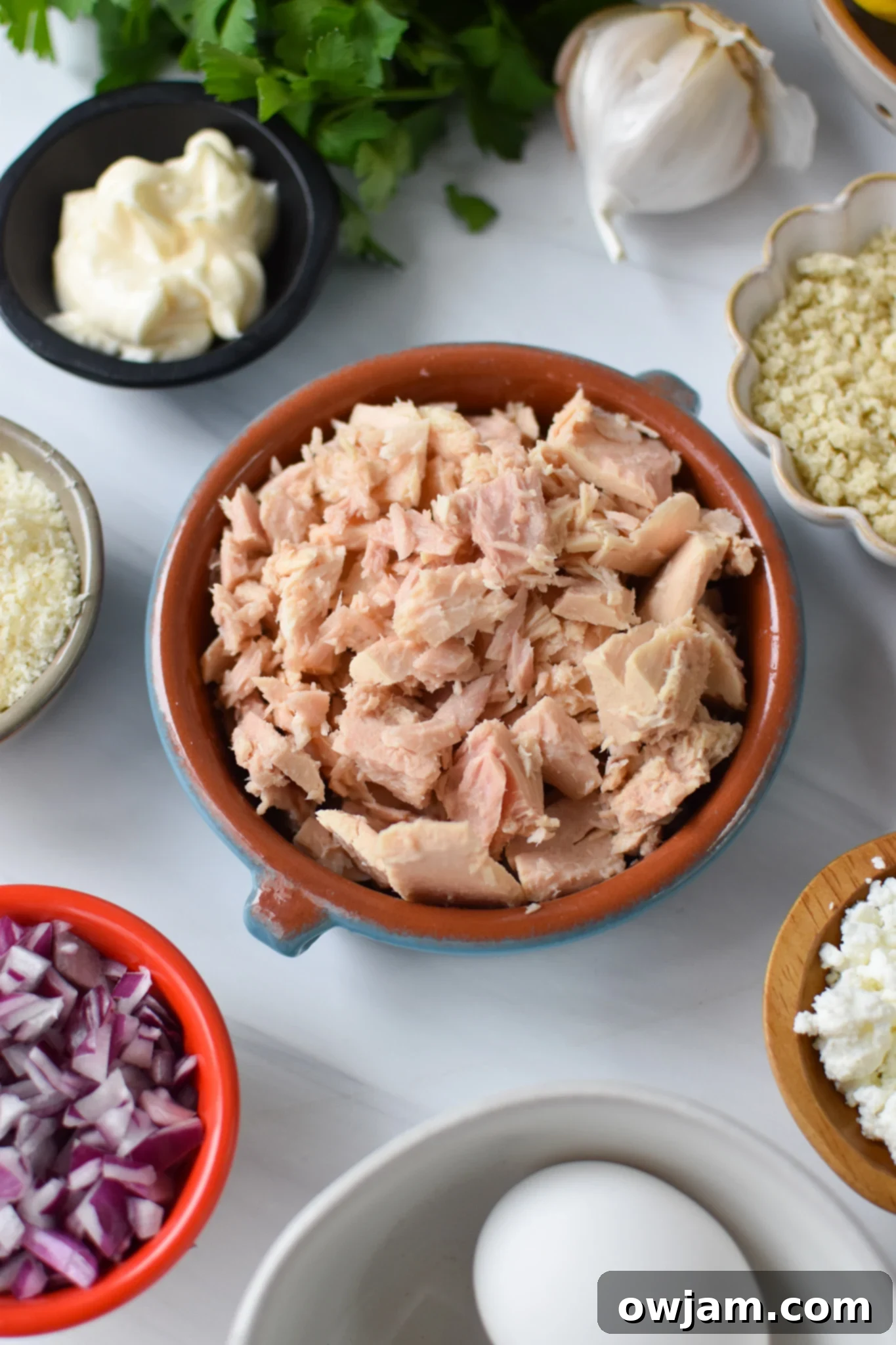 All the fresh ingredients for Mediterranean Tuna Patties laid out on a wooden board.