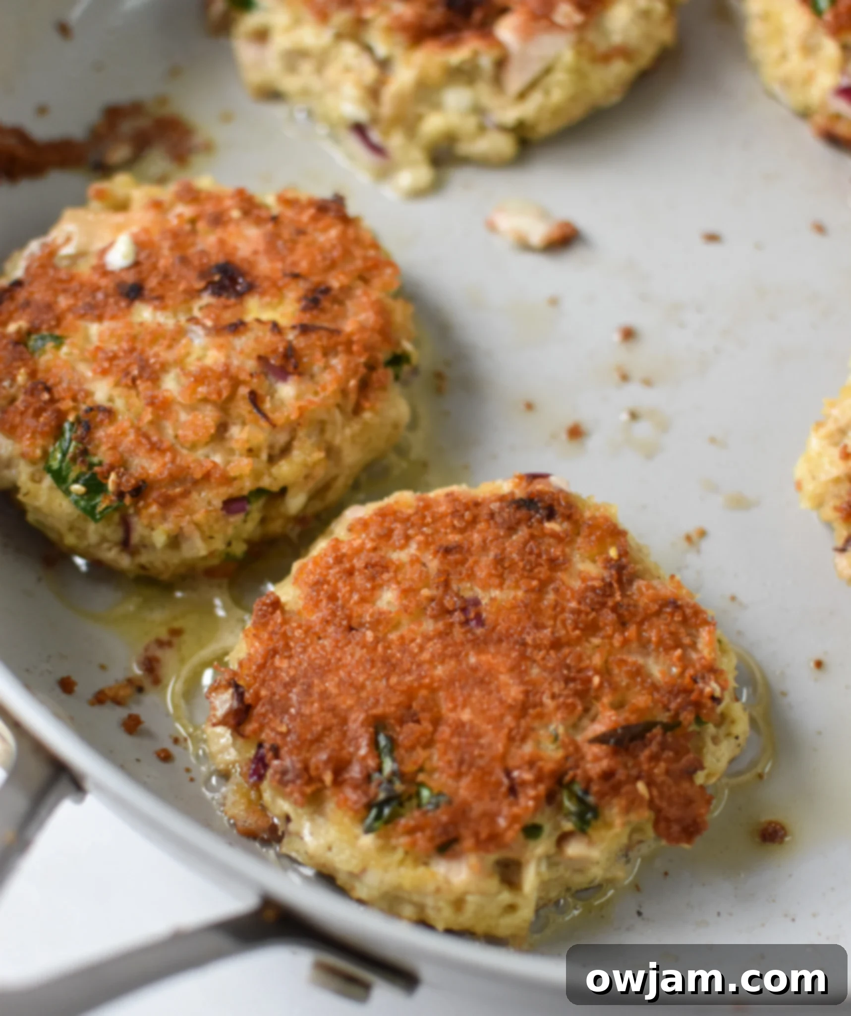 Mediterranean Tuna Patties cooking in a skillet, turning golden brown.