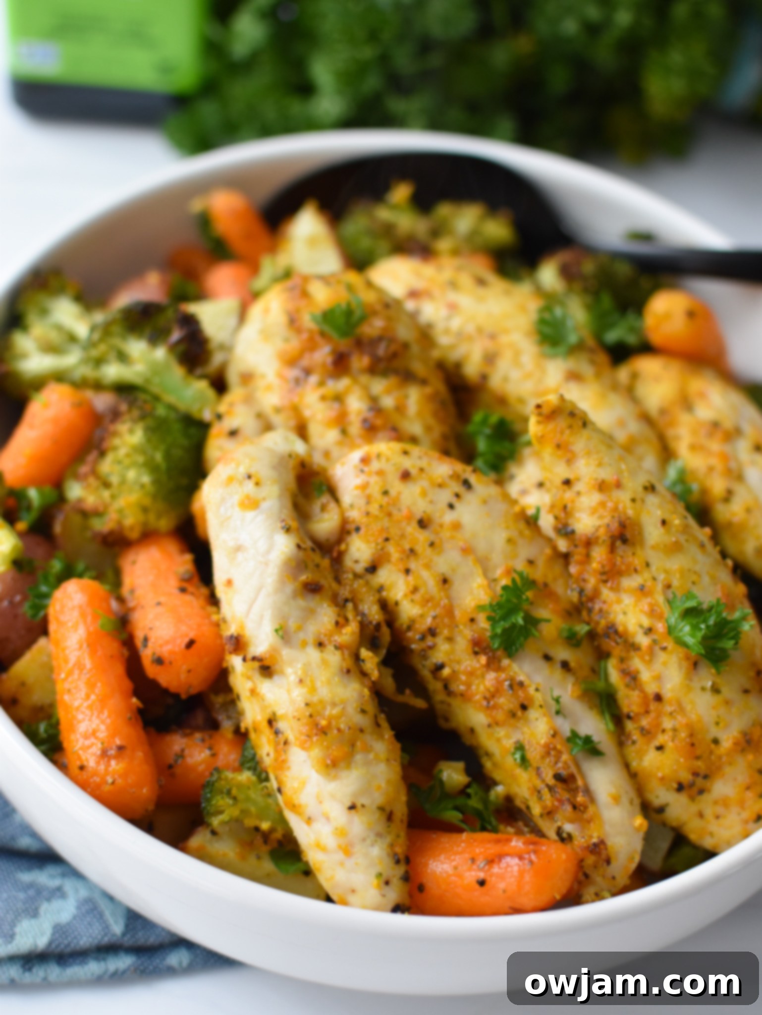 One-Pan Lemon Parmesan Chicken Tenders 4 Raw chicken tenderloins and cut vegetables in a large mixing bowl, ready for seasoning.