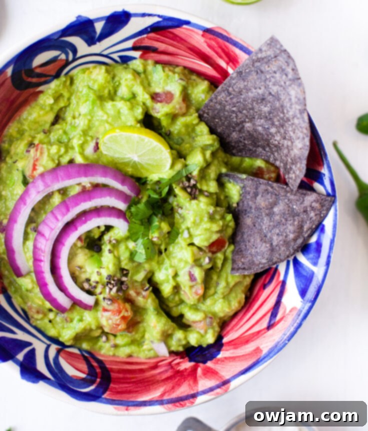 23 Irresistible Sides to Elevate Your Taco Night 15 A bowl of creamy, homemade Easy Guacamole, garnished with fresh cilantro, diced red onion, and lime wedges.