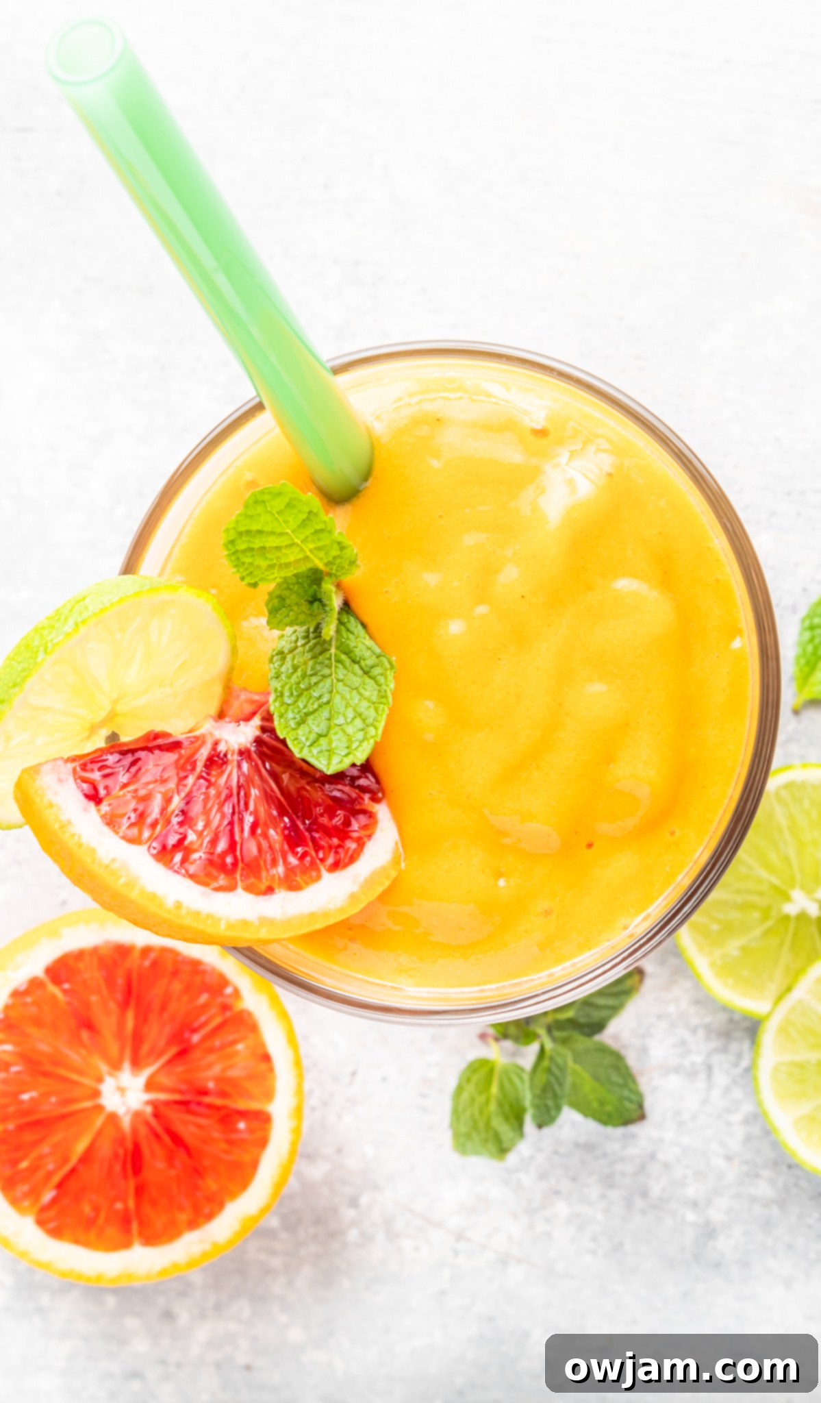 Orange Smoothie in a glass with a straw, garnished with fresh mint.