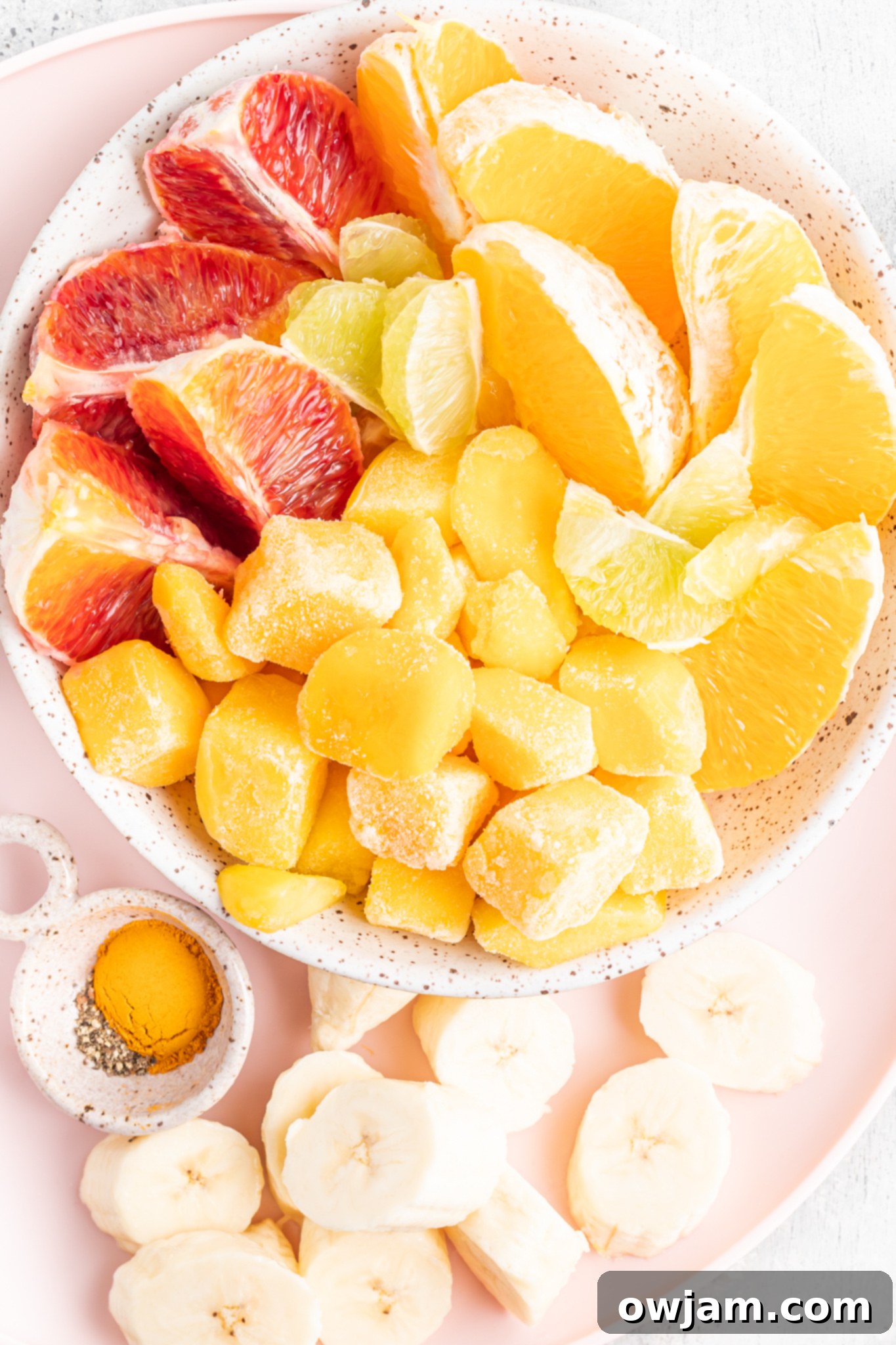 Fresh ingredients for Orange Smoothie: oranges, mango, banana, lime, and turmeric.
