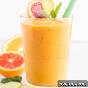 A refreshing Orange Smoothie in a glass, with fresh orange slices and mint nearby.