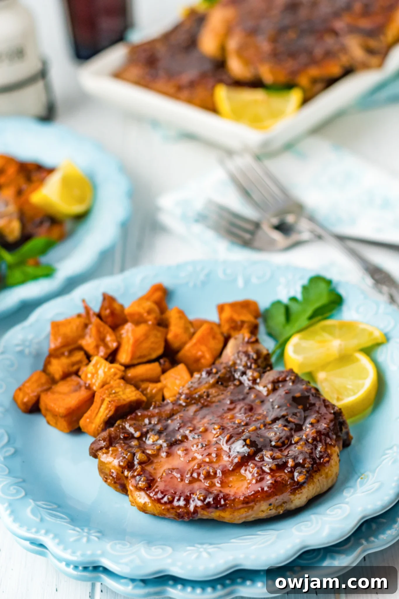Maple Bourbon Glazed Pork Chops Recipe 2 Maple Bourbon Pork Chops Recipe on a blue plate, garnished and ready to serve.