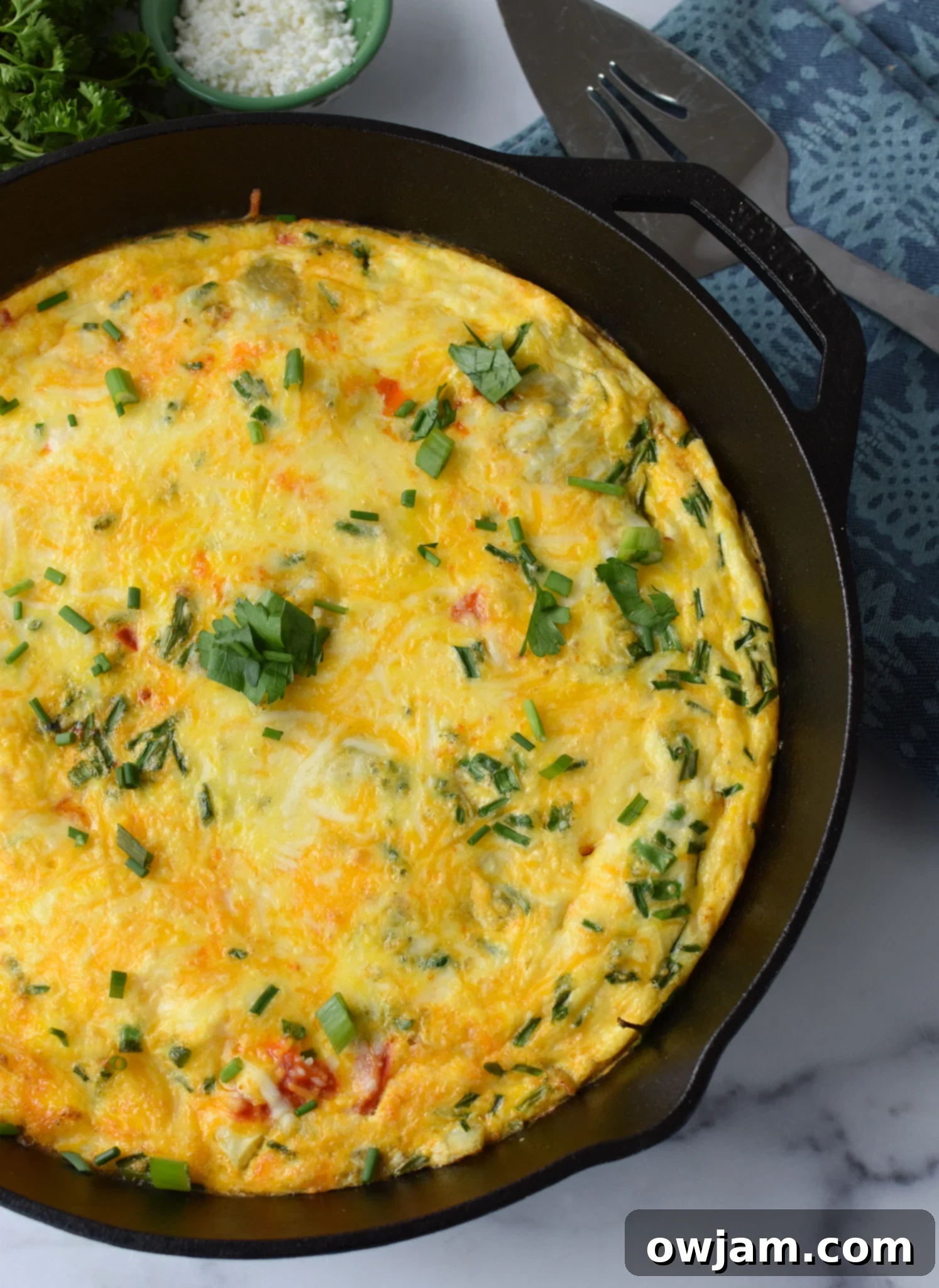 Mediterranean Vegetable Frittata Recipe with parsley. A close-up of a slice of Mediterranean frittata, garnished with fresh parsley, highlighting its wholesome ingredients and inviting appearance.