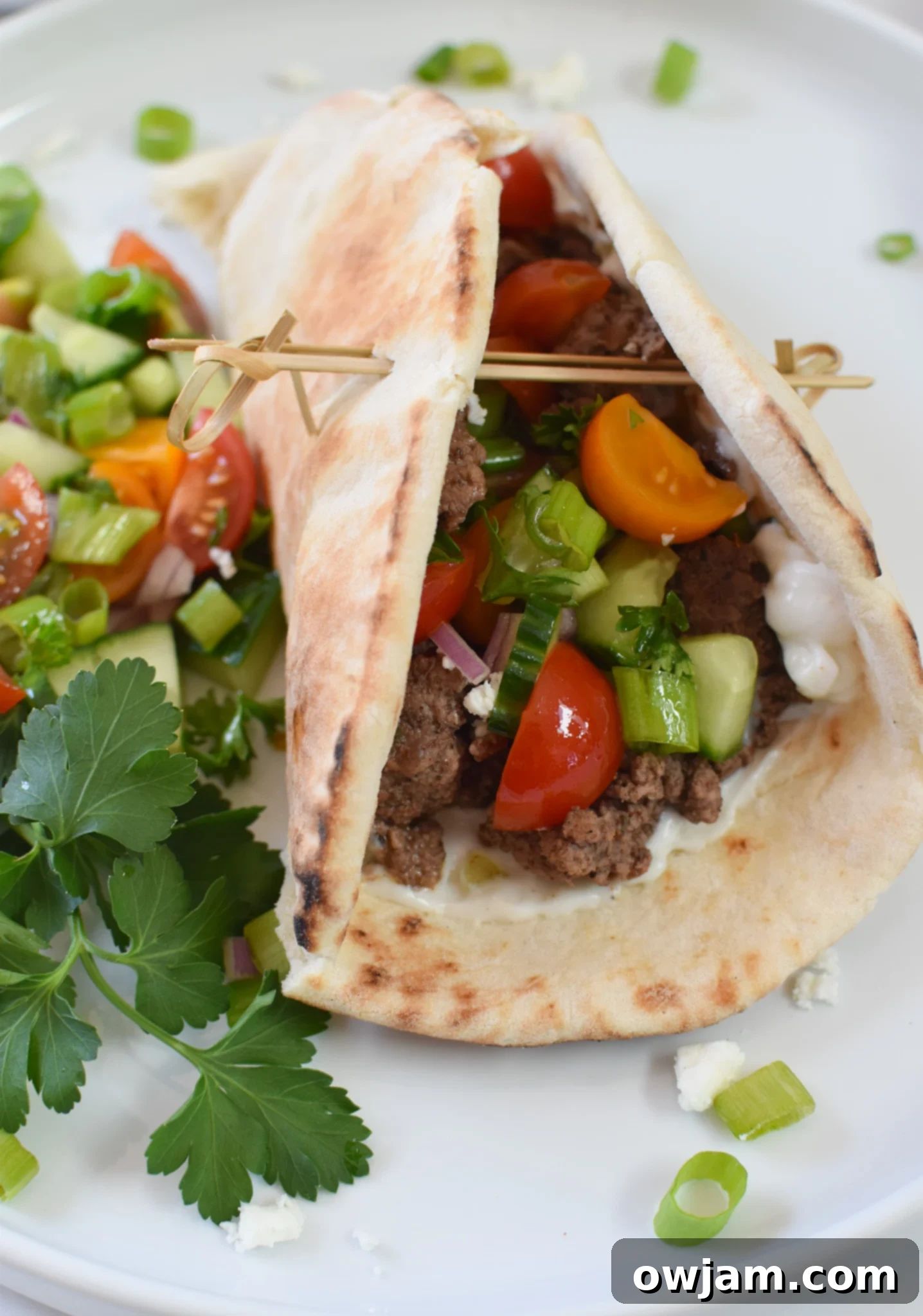 Spiced Lamb Pita Pockets 4 Cooked spiced ground lamb nestled inside a warm pita bread, ready for toppings in this Mediterranean recipe.