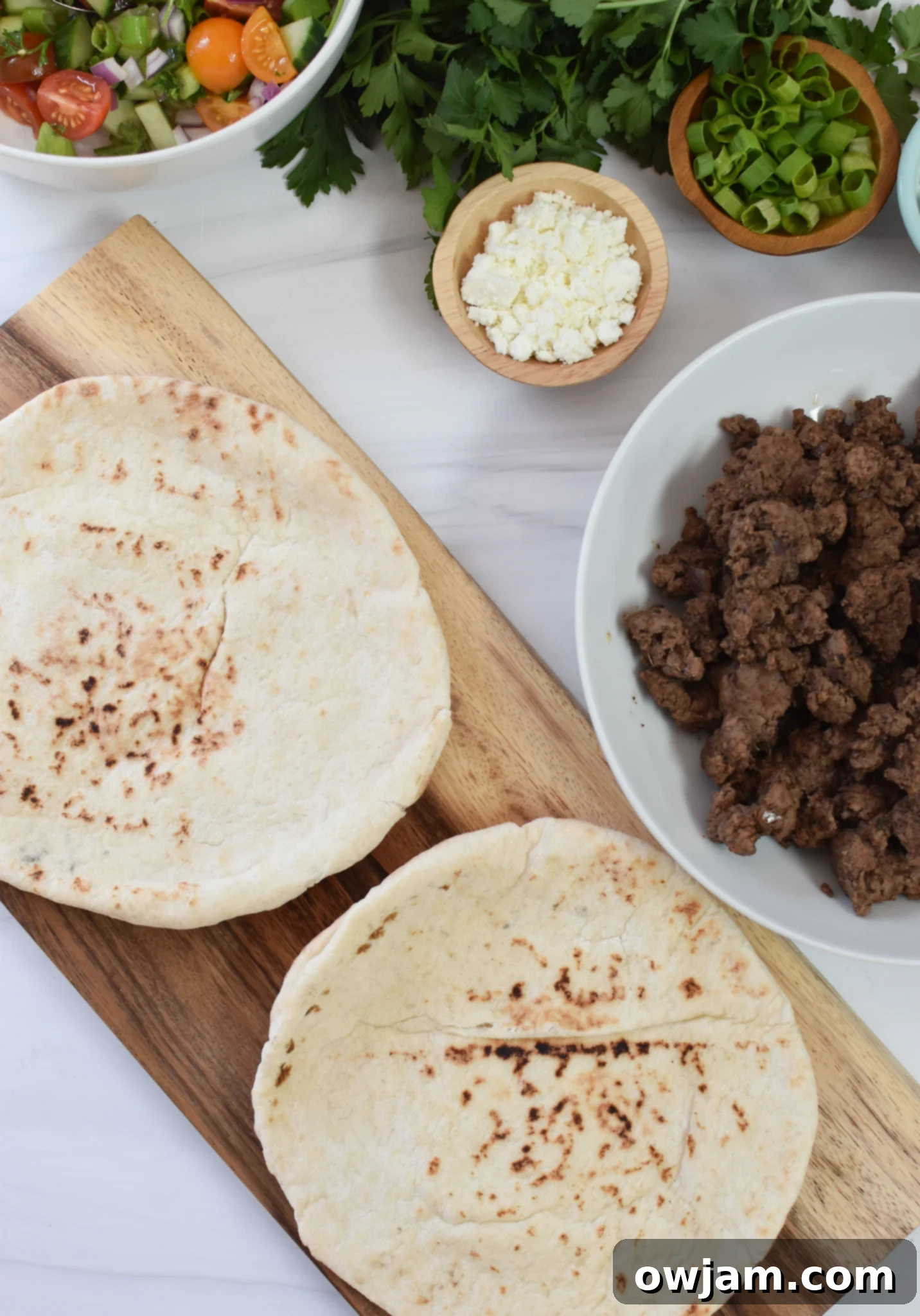 Spiced Lamb Pita Pockets 5 Assortment of warm pita breads arranged on a cutting board, ready to be filled with spiced lamb and fresh toppings.