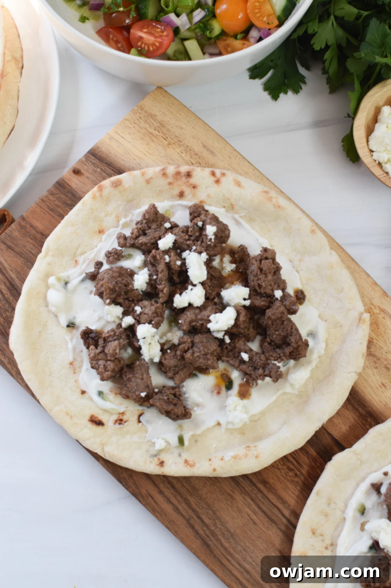 Spiced Lamb Pita Pockets 6 Close-up of a Spiced Ground Lamb Pita, beautifully garnished with fresh Greek toppings and creamy tzatziki.
