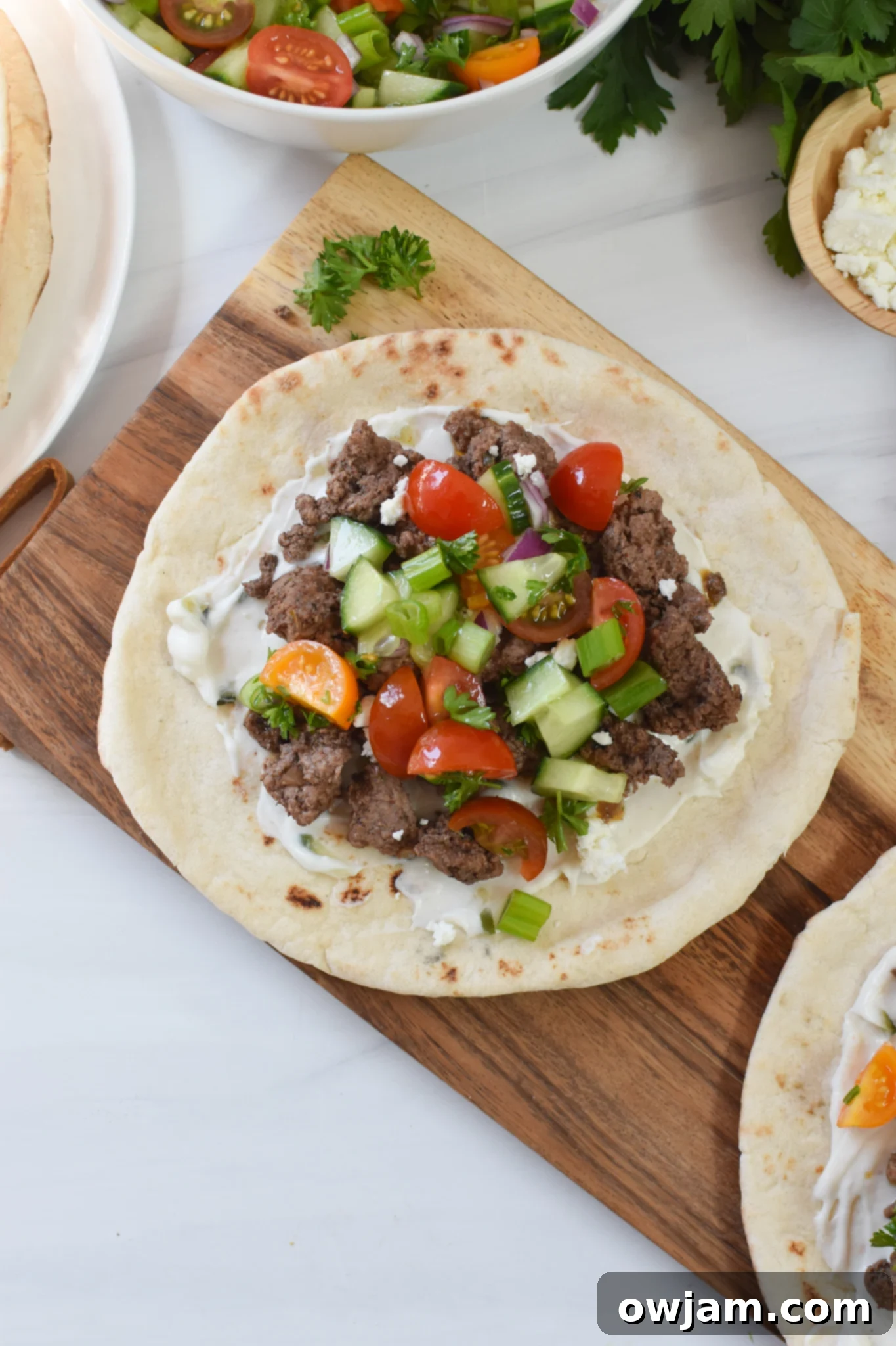 Spiced Lamb Pita Pockets 7 Spiced Ground Lamb Pita garnished with a generous amount of fresh Greek-style topping and crumbled feta.
