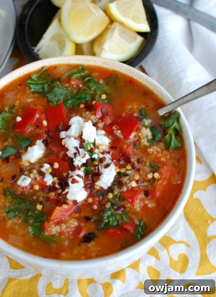 Hearty Tomato Red Pepper Bulgur Soup in a white bowl with a spoon