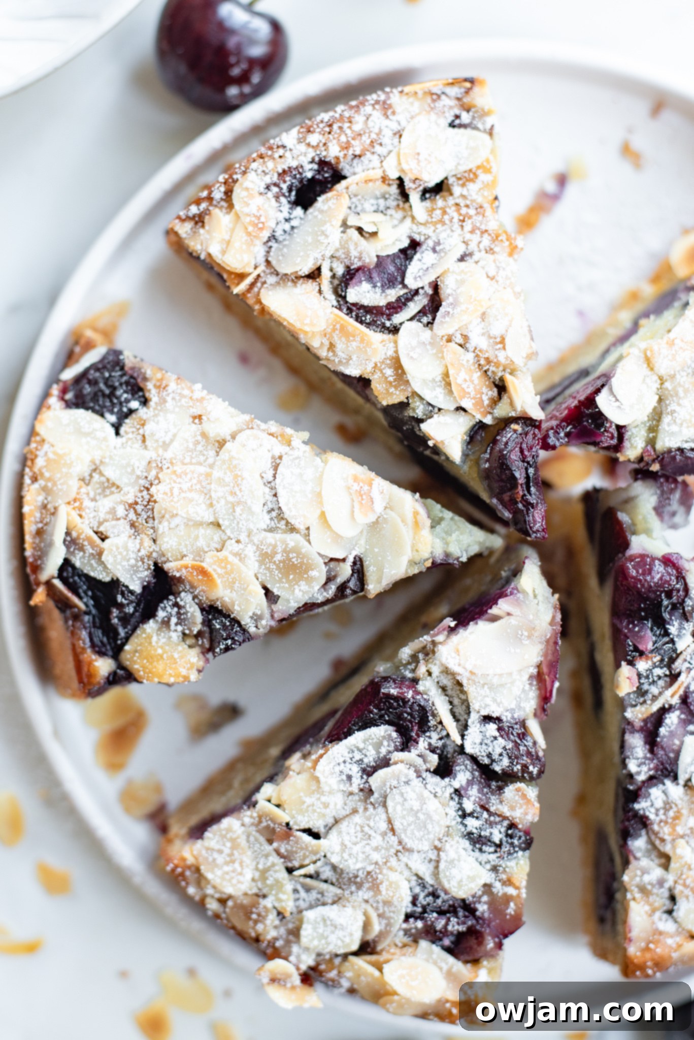 Cherry Almond Cake, cut into generous slices, revealing the beautiful pattern of cherries and almonds on top.