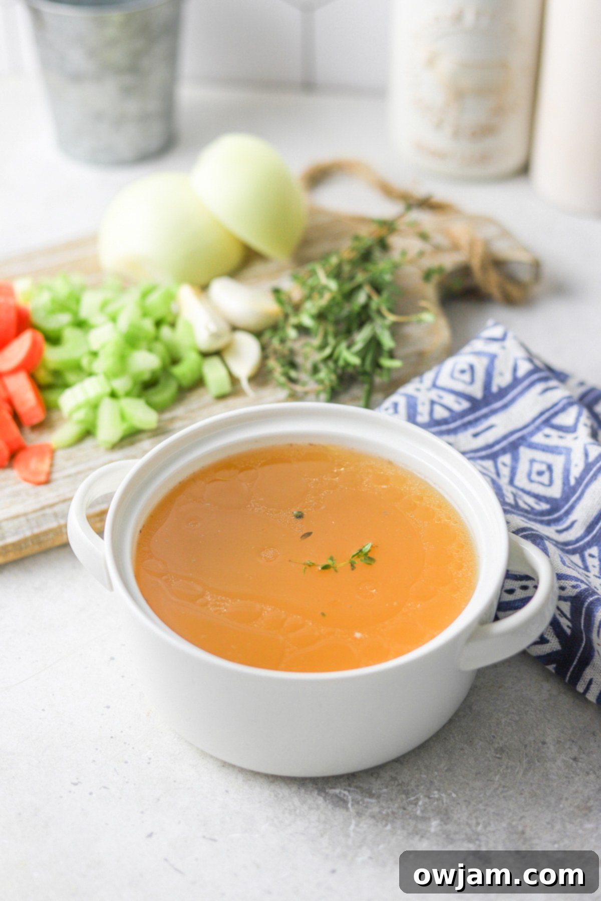 Slow-Simmered Chicken Broth 3 Homemade Chicken Broth in a glass jar with a blue napkin, showcasing its clarity.