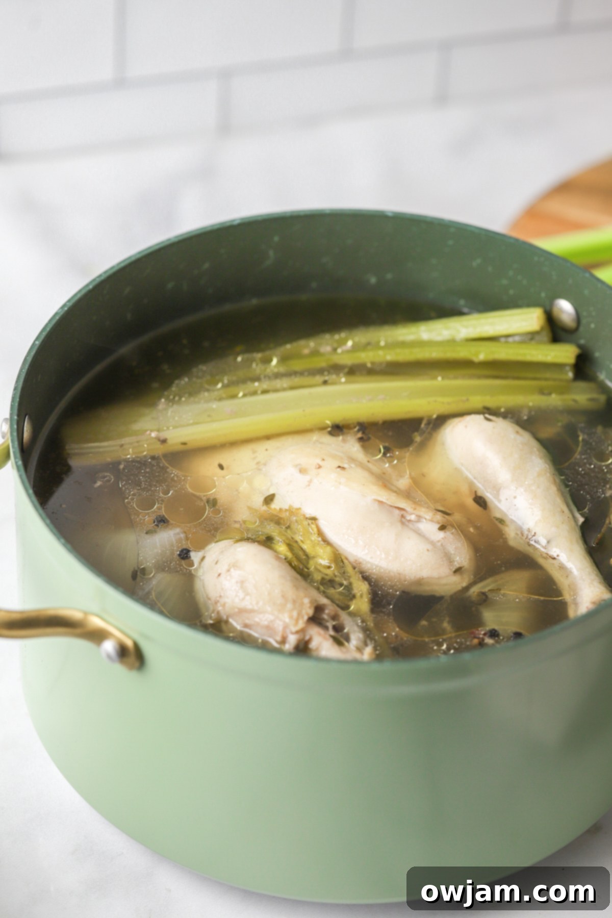 Slow-Simmered Chicken Broth 7 Homemade Chicken Broth ingredients simmering in a pot with water and herbs.