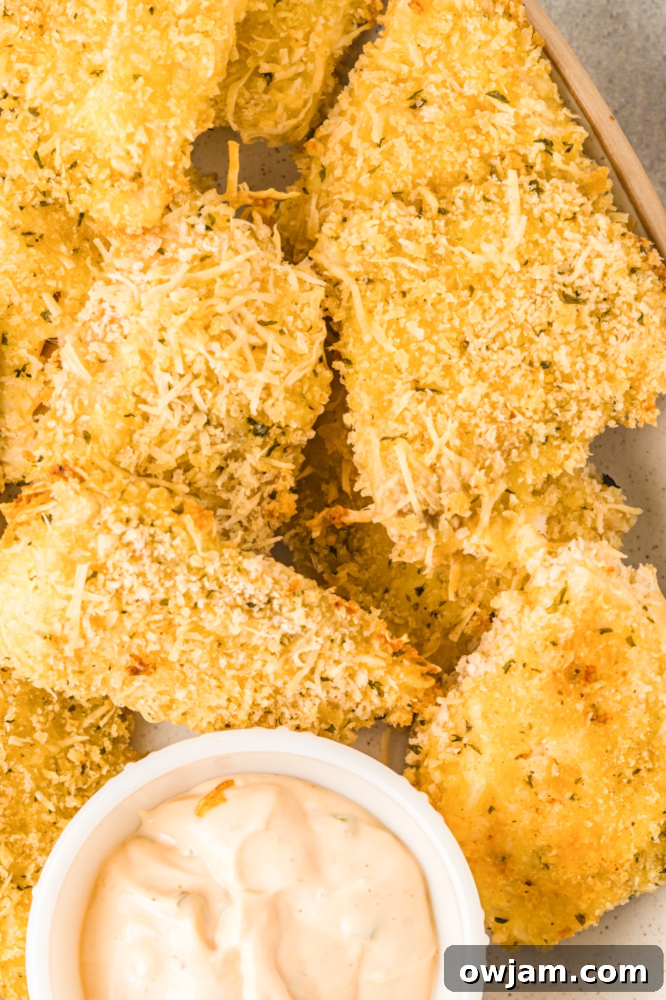 Baked Parmesan Fish Sticks with dip and lemon wedges.
