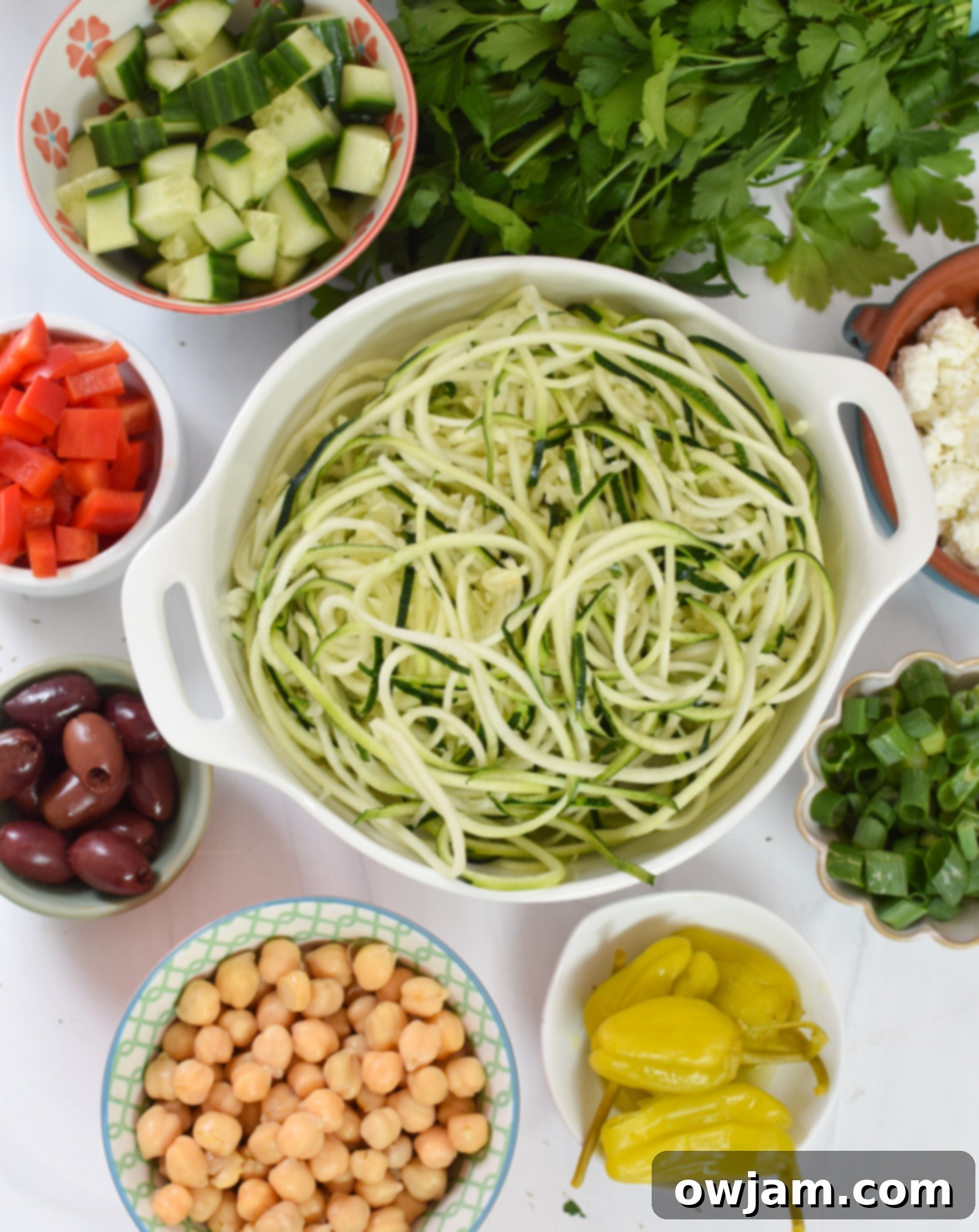 Sun-Kissed Zucchini Pasta Medley 3 Various fresh ingredients for Mediterranean Zucchini Pasta Salad laid out on a wooden surface.