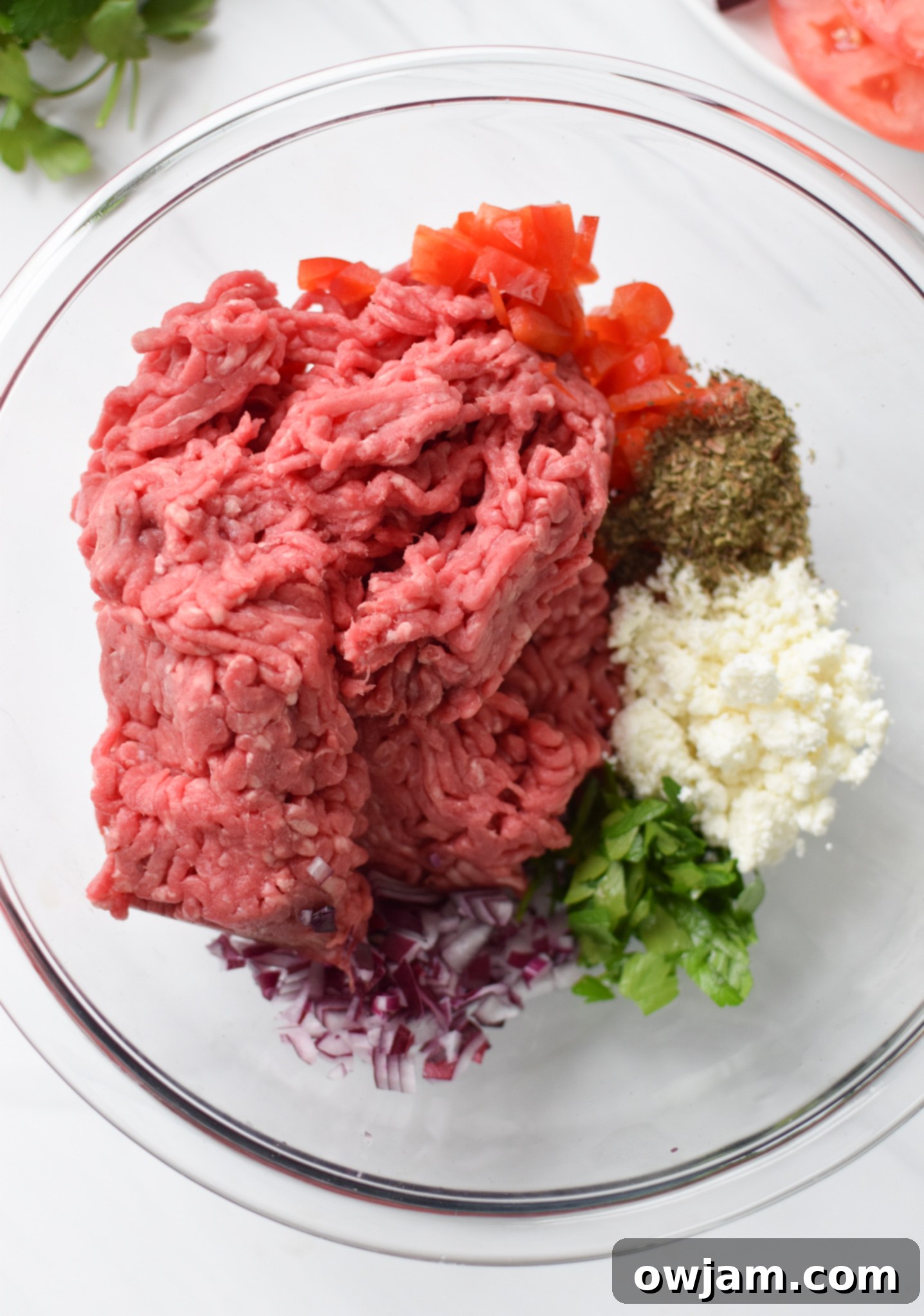 Feta Burger ingredients being mixed by hand in a large bowl.