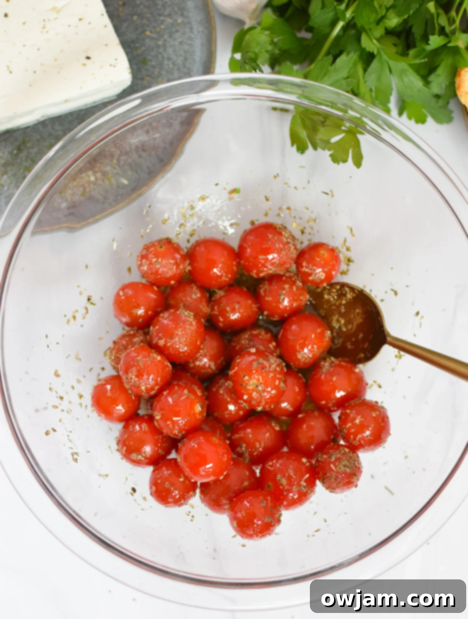 Simple Baked Feta Perfection 5 Cherry tomatoes tossed with olive oil in a mixing bowl for the Easy Baked Feta Recipe.