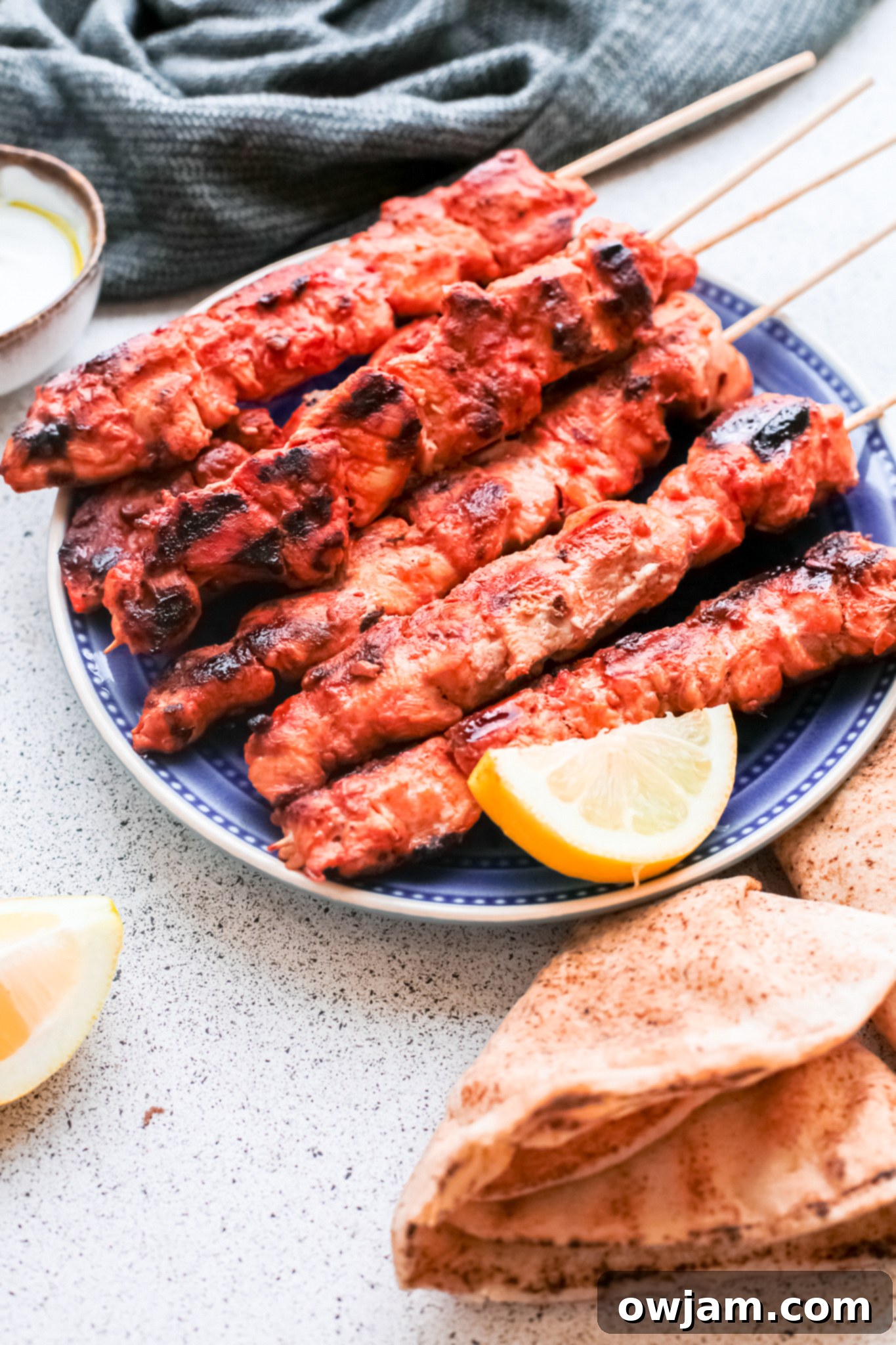 Authentic Lebanese Chicken Skewers 5 A single Lebanese Chicken Kebab skewer on a plate with a lemon wedge.