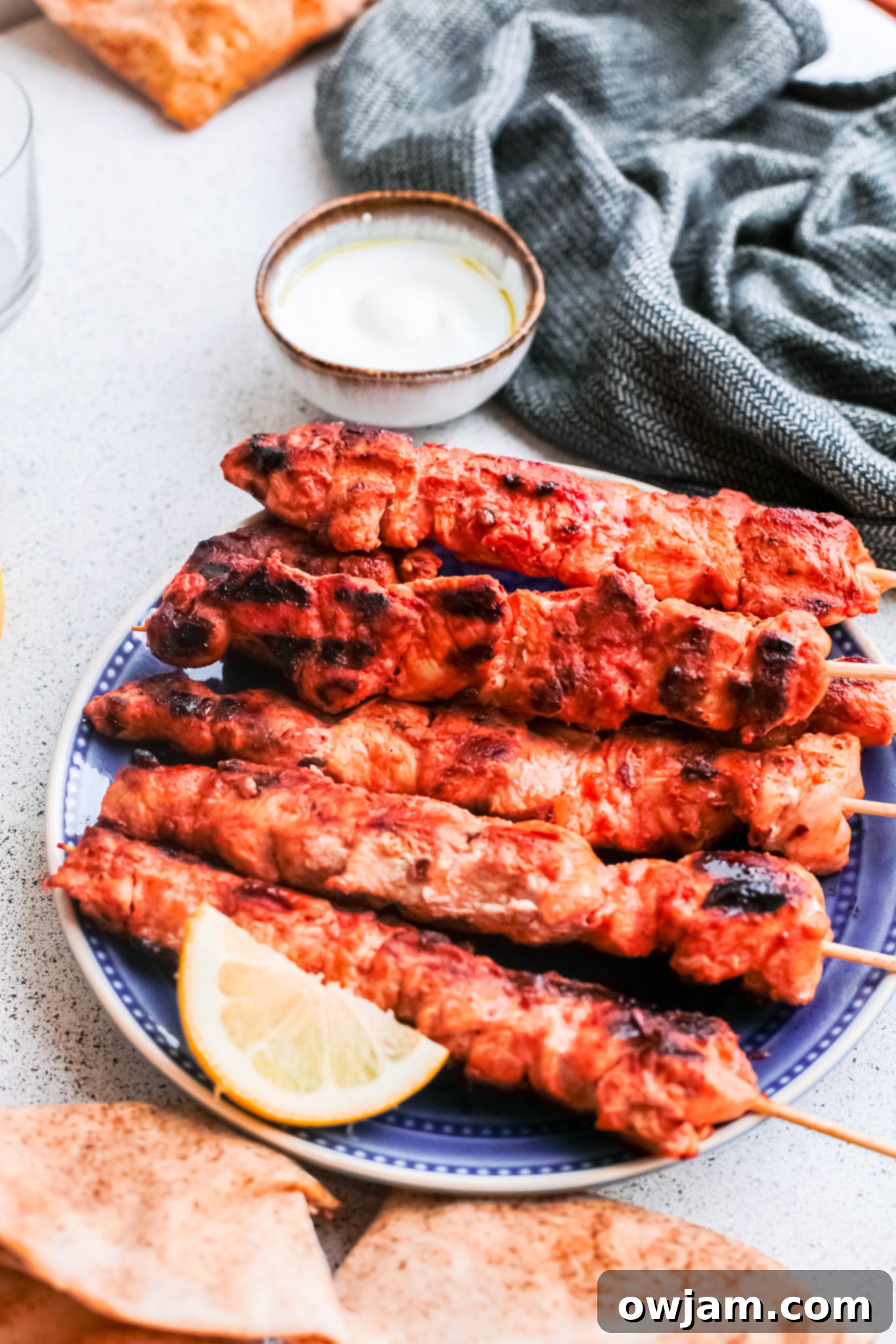 Authentic Lebanese Chicken Skewers 7 Lebanese Chicken Kebabs served on a blue platter with fresh parsley and lemon wedges.
