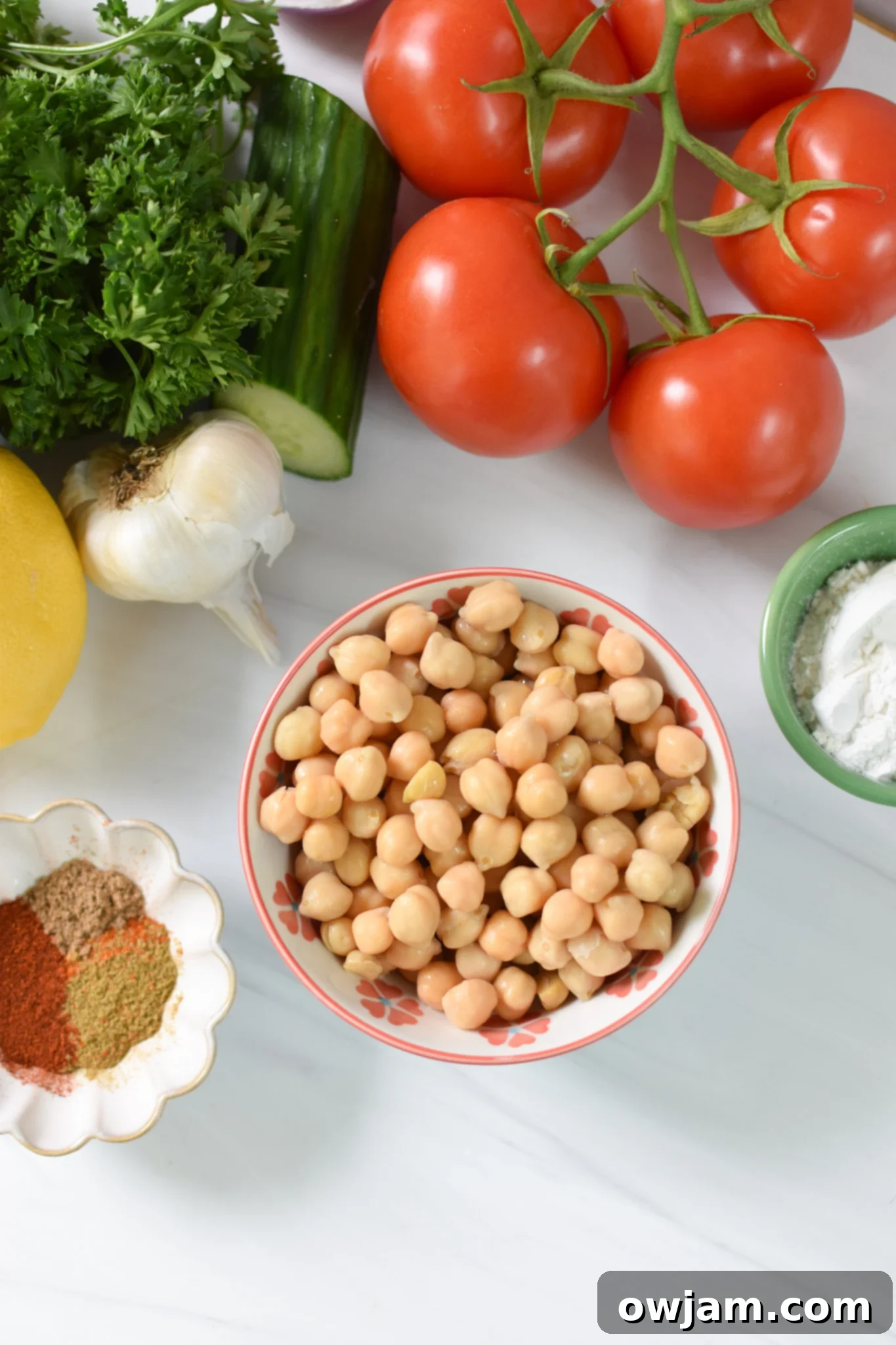 A vibrant selection of fresh ingredients including chickpeas, red onion, parsley, and various spices laid out on a wooden board, ready for making falafel waffles.
