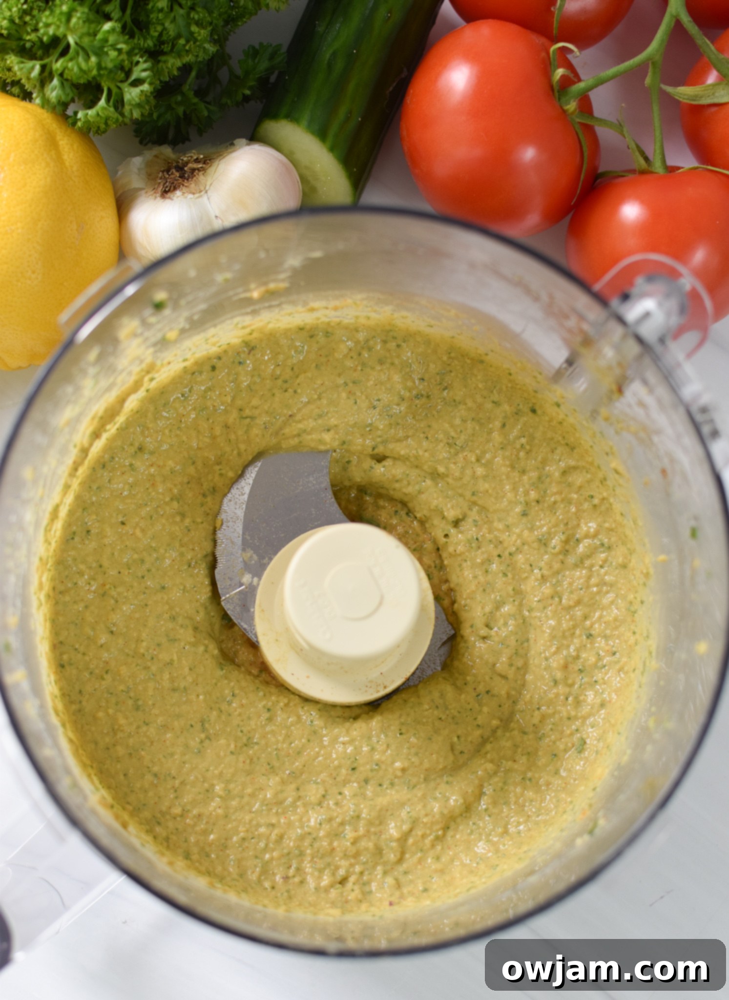 The blended falafel mixture in a food processor, showing a coarse yet cohesive texture, ready for the waffle iron.
