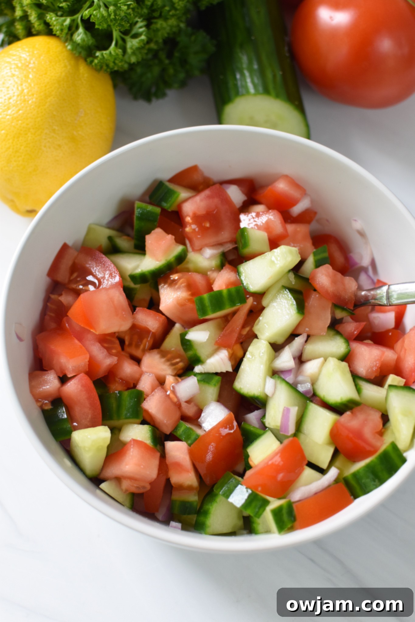 A vibrant Lebanese salad with diced tomatoes, cucumbers, and red onion, dressed and ready to be served with falafel waffles.