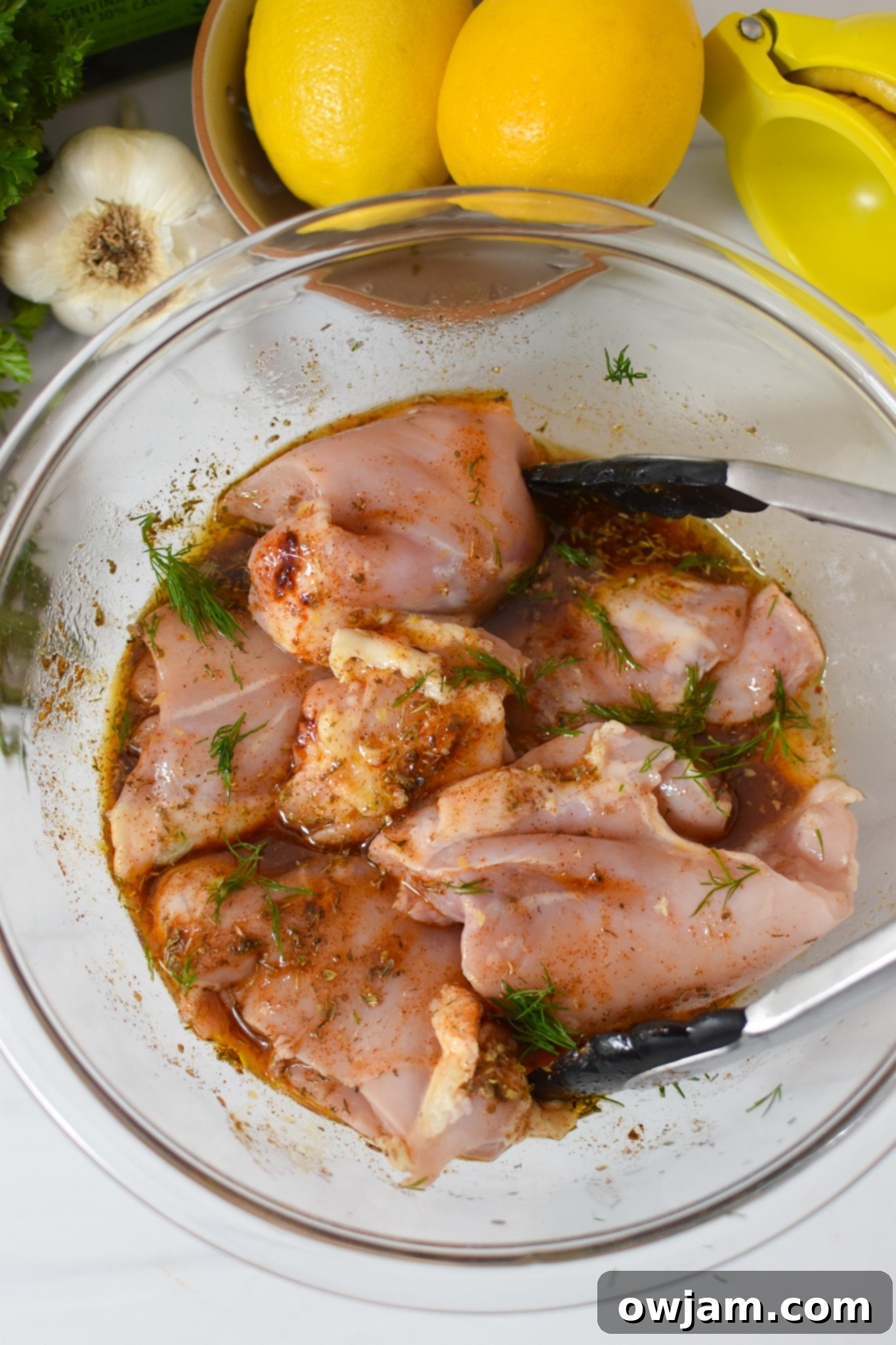 Sun-Kissed Grilled Chicken Greek Salad 6 Marinated chicken thighs resting in a clear bowl, ready for grilling.
